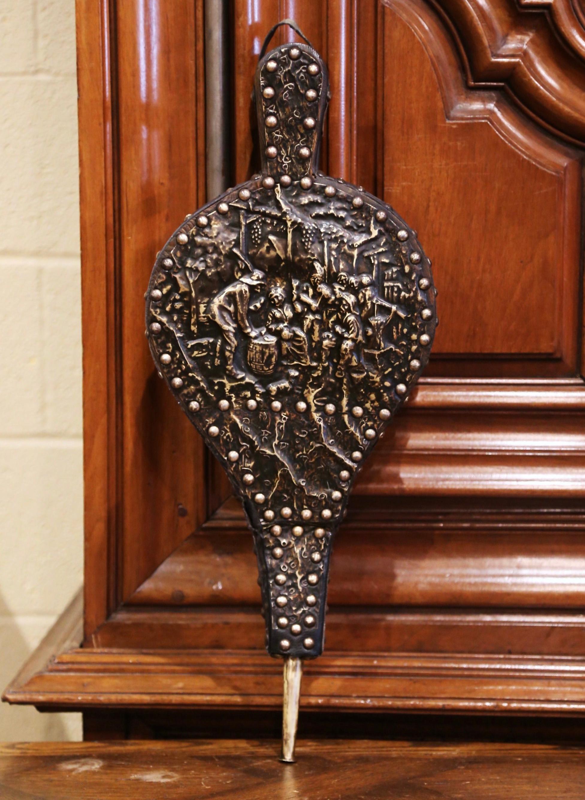 Decorate a fireplace and active the flames with this elegant and useful antique bellows. Crafted in Brittany, France, circa 1880, the fireplace essential features a repousse brass top surface depicting a pastoral tavern scene in the manner of