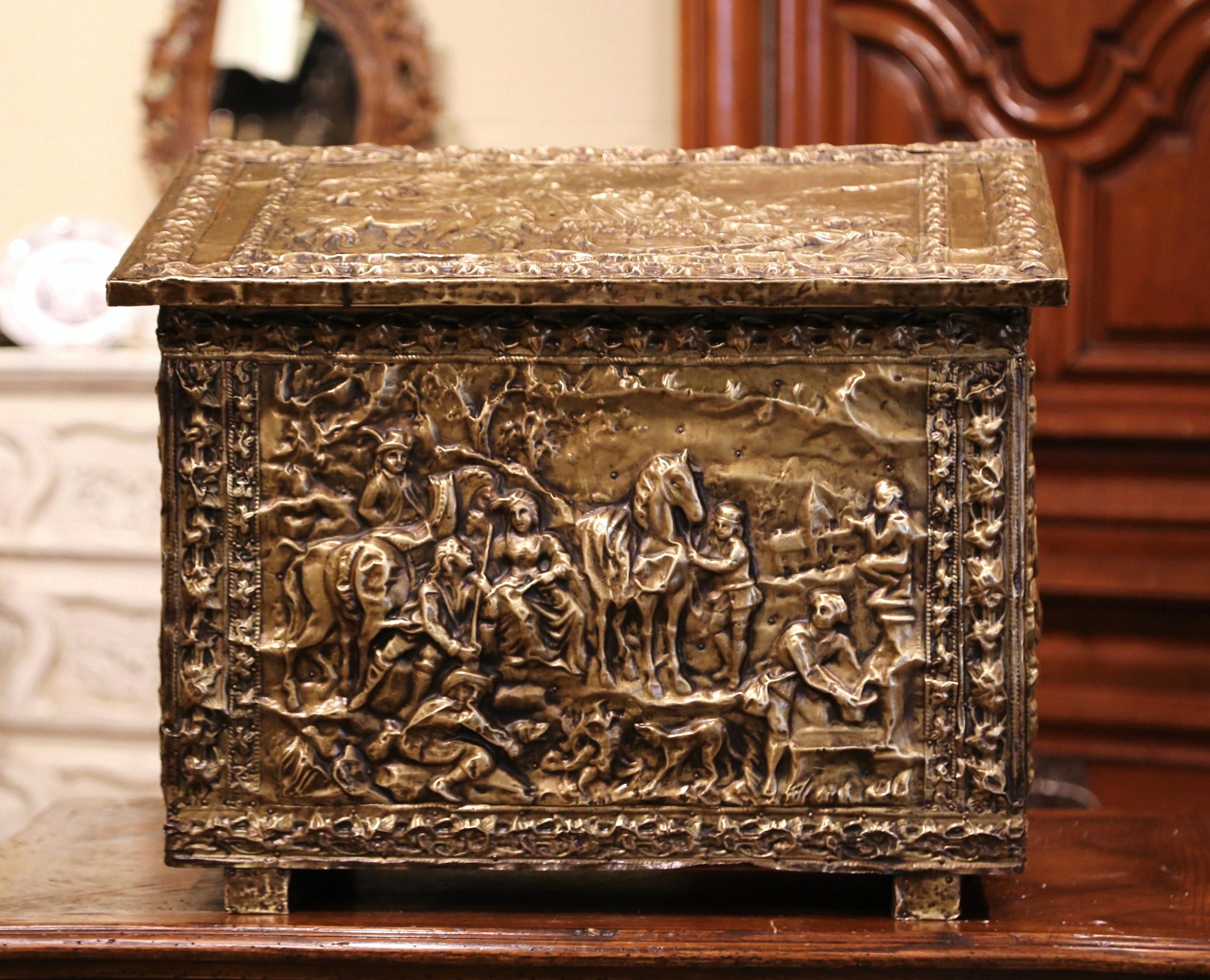 Crafted in France, circa 1870, the antique wooden and brass coffer is decorated with repousse pastoral scenes on all four sides and features a slant top opening to inside storage. The decorative trunk is in excellent condition and has the original