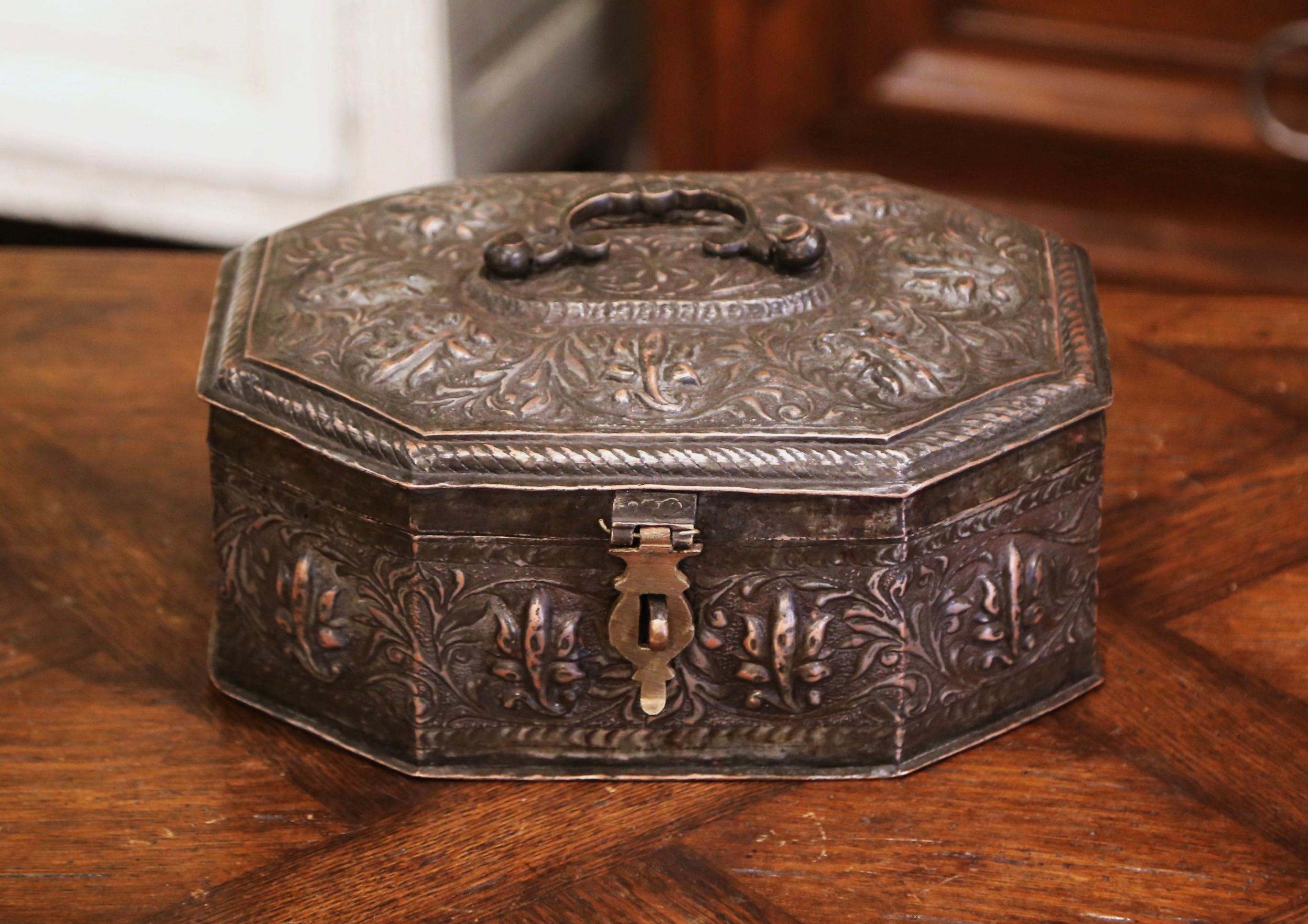 Fabriquée dans le sud de la France vers 1860, de forme octogonale, cette boîte ancienne est construite en métal avec une finition argentée et des motifs floraux et feuillus repoussés. Le coffret décoratif avec poignée décorative, comporte cinq