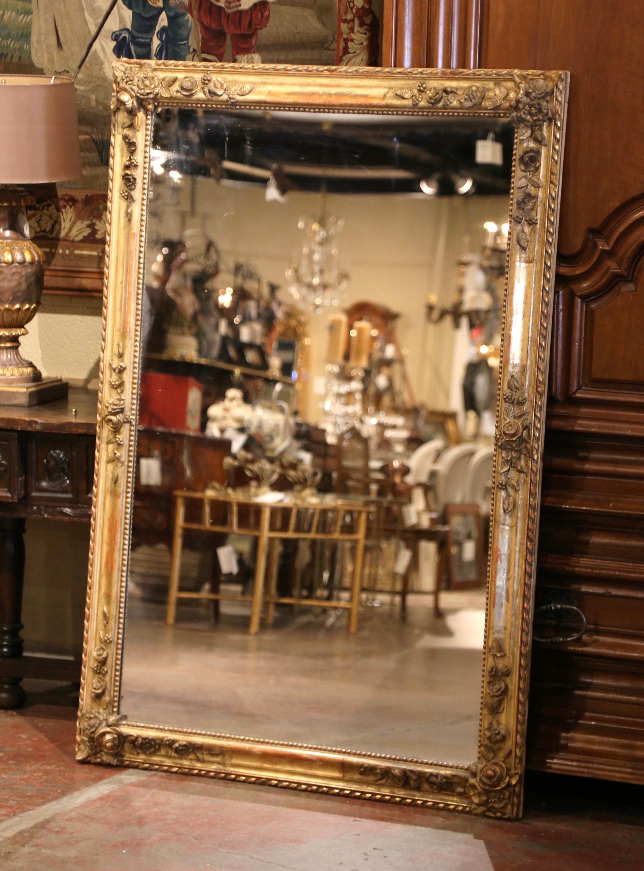 This elegant antique gilt mirror was created in France, circa 1820. Rectangular in shape, and almost 5.5 feet long, the large mirror features exquisite hand carved floral, leaf and fruit motifs in high relief all around, and embellished with a
