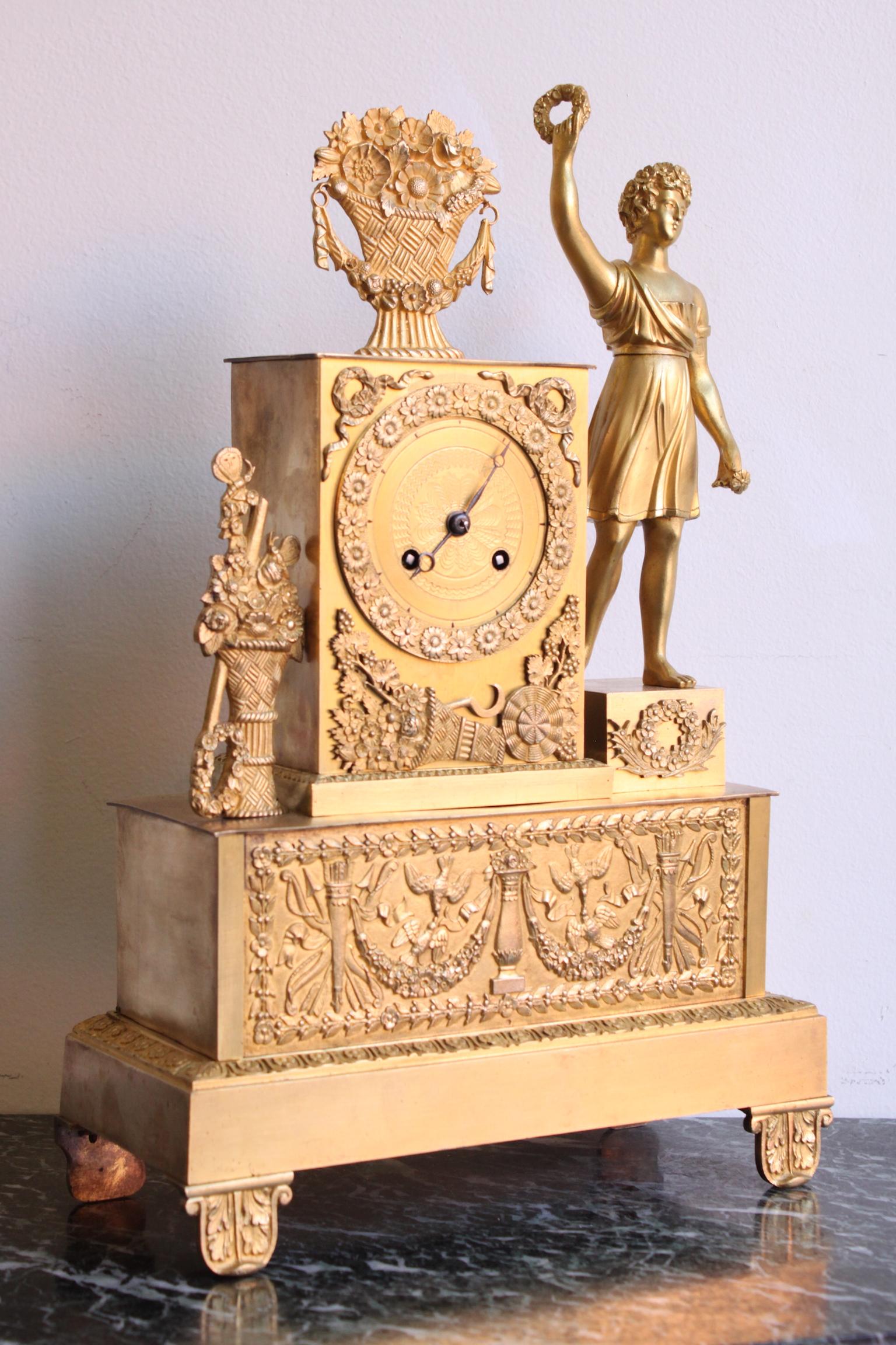 19th century French Restauration clock, decorated with a man holding a laurel wreath. Gilding from the time. 
Dimensions: Width 25cm, depth 10cm, height 39cm.