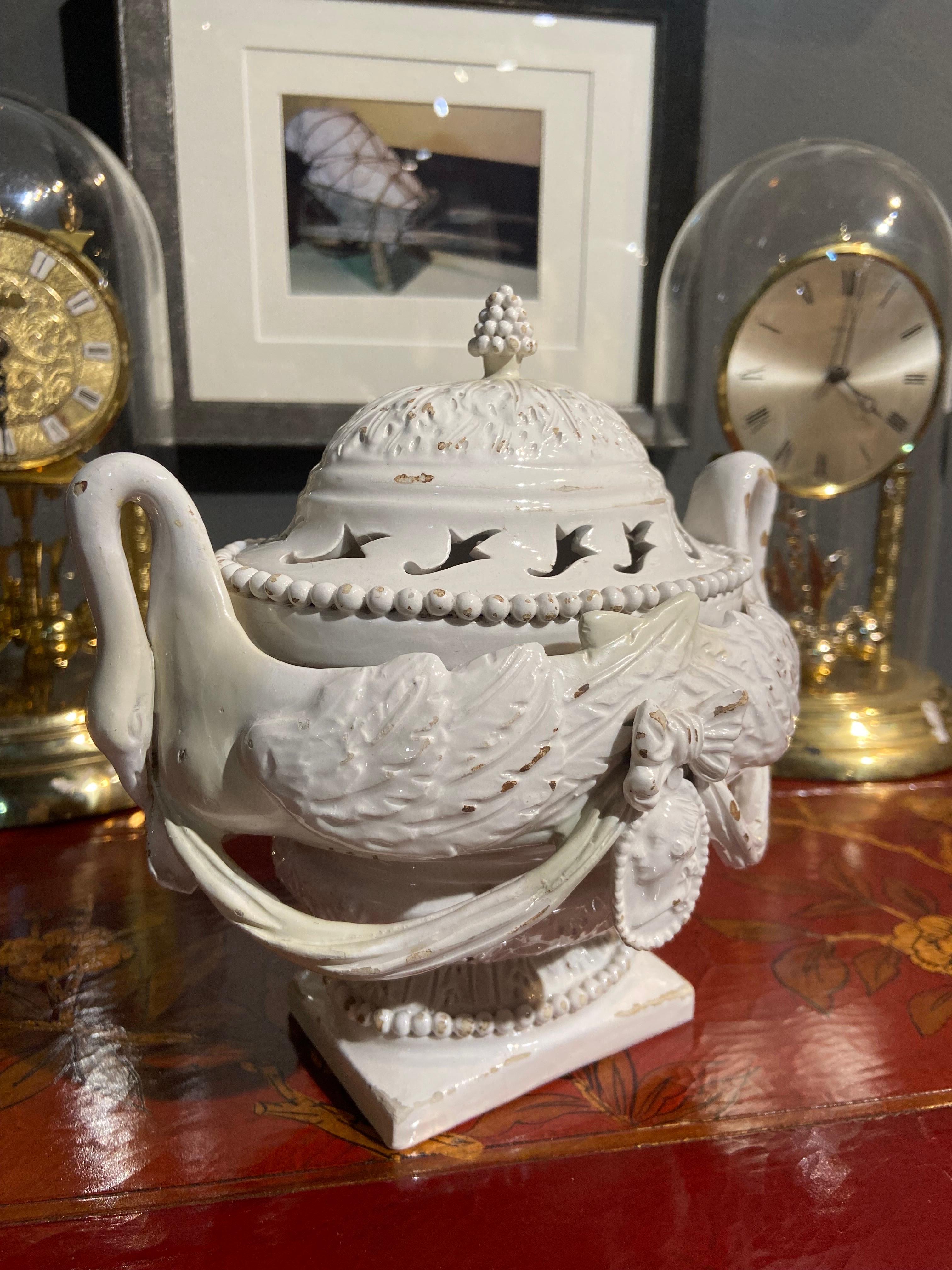 Extraordinary white ceramic centerpiece representing two beautiful swans turned back to each other to form an oval bowl resting one large square leg, decorated with a ribbon and a portrait in the center. The top of the item is as elegant as the base