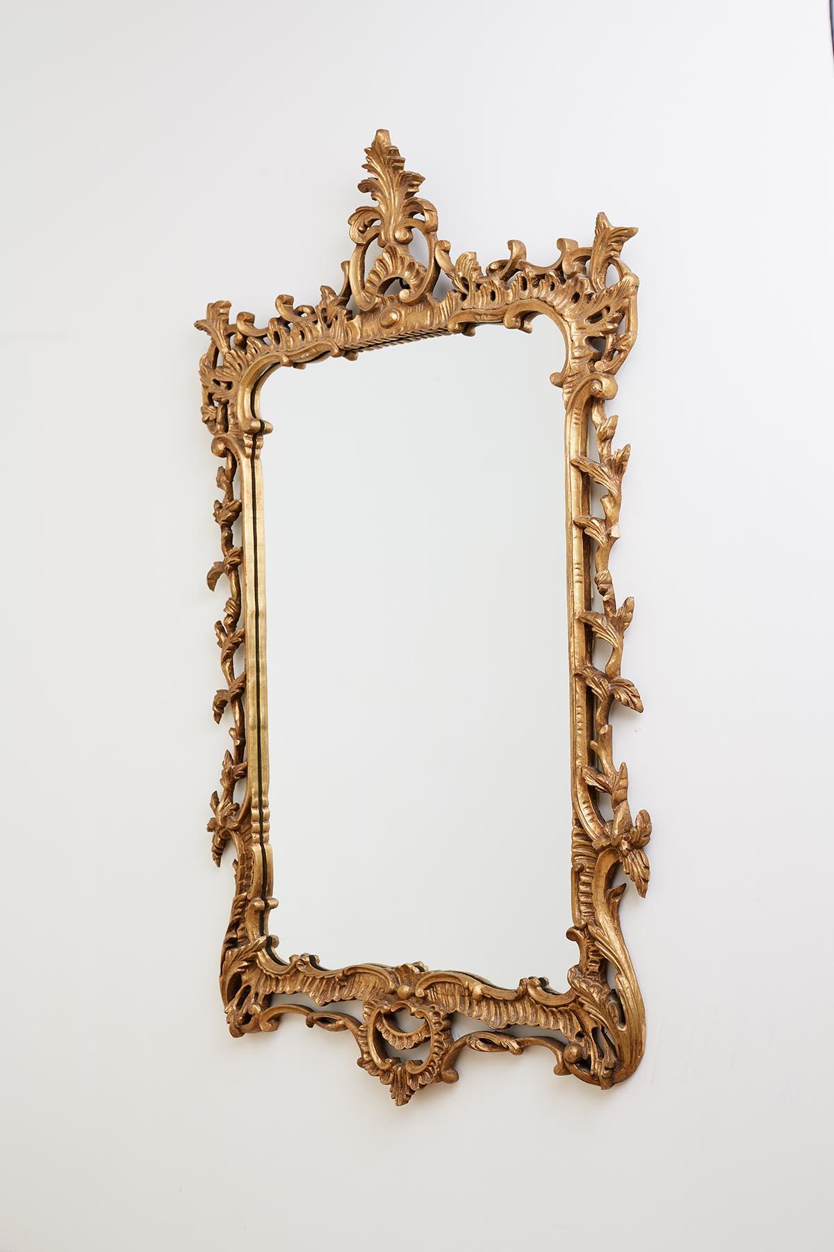 Attractive 19th century French giltwood carved mirror made in the Rococo taste. Features a frame decorated with large scroll designs and acanthus leaf vines. The top and bottom are centred by C scrolls. The top having an acanthus spray. Large iron