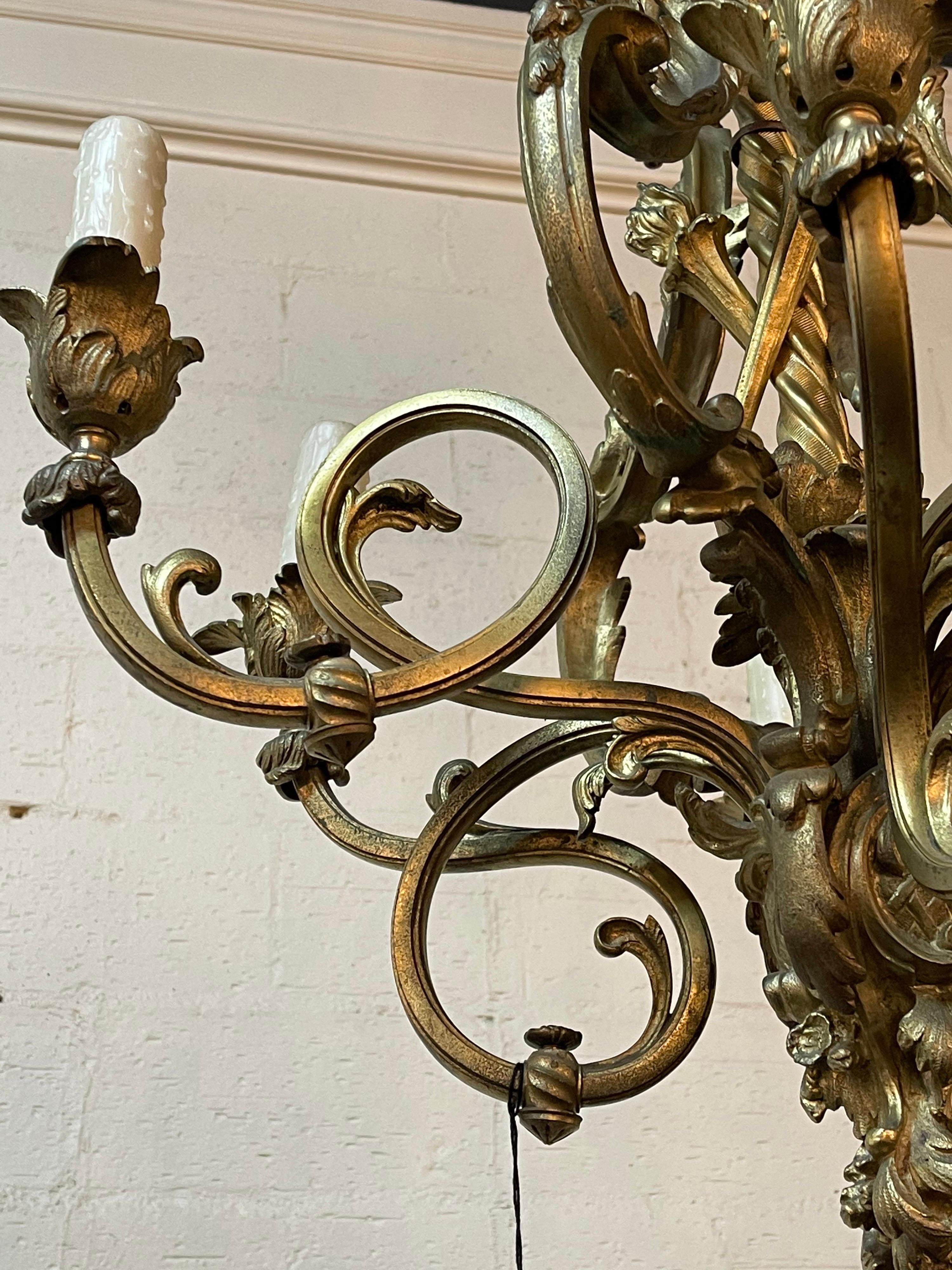 Particularly fine, circa 1880 French heavy cast gold-gilded bronze chandelier. The acanthus motif canopy above an open cage with twisted stem surmounted by bronze flamed torches.

The scrolling arms end in foliate designed bobeche with candle