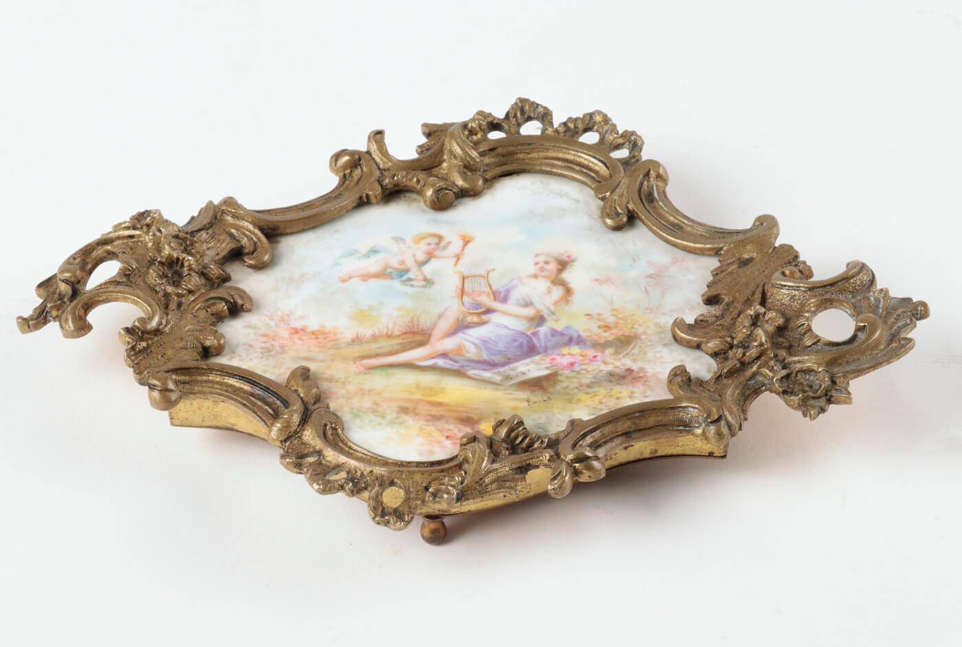 Beautiful dish, a so-called 'vide-poche'.
Originating from France, dated circa 1880-1900. The porcelain is hand painted with a romantic scene. There is also a small signature on 'Emil'. The richly carved bronze rim has clear characteristics of the