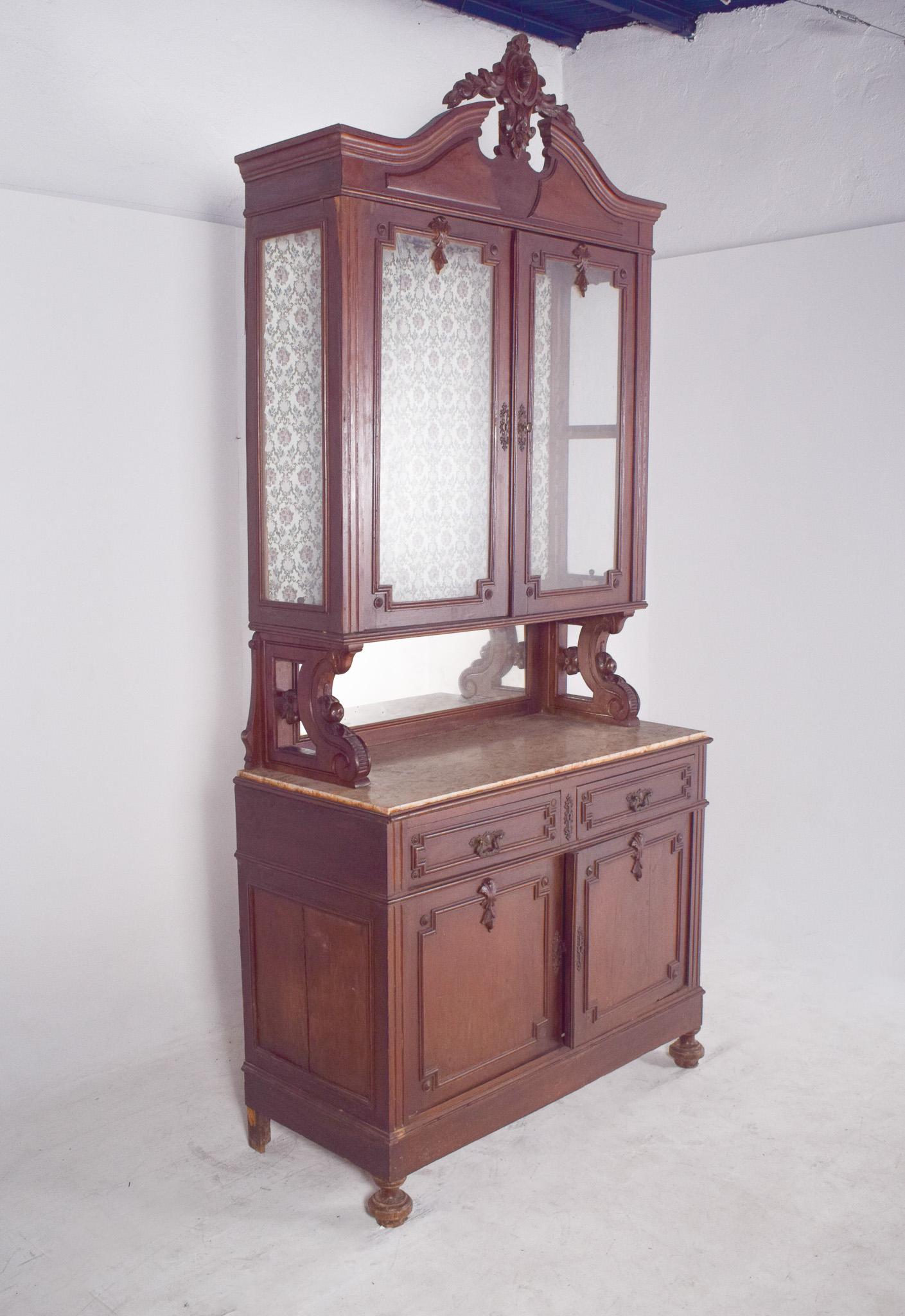 Armoire romantique à deux corps. En bois sculpté, la partie supérieure comporte deux portes vitrées avec un cadre sculpté, surmonté d'un arc floral incurvé avec un décor central en relief floral et en médaillon, typique de la décoration du XIXe