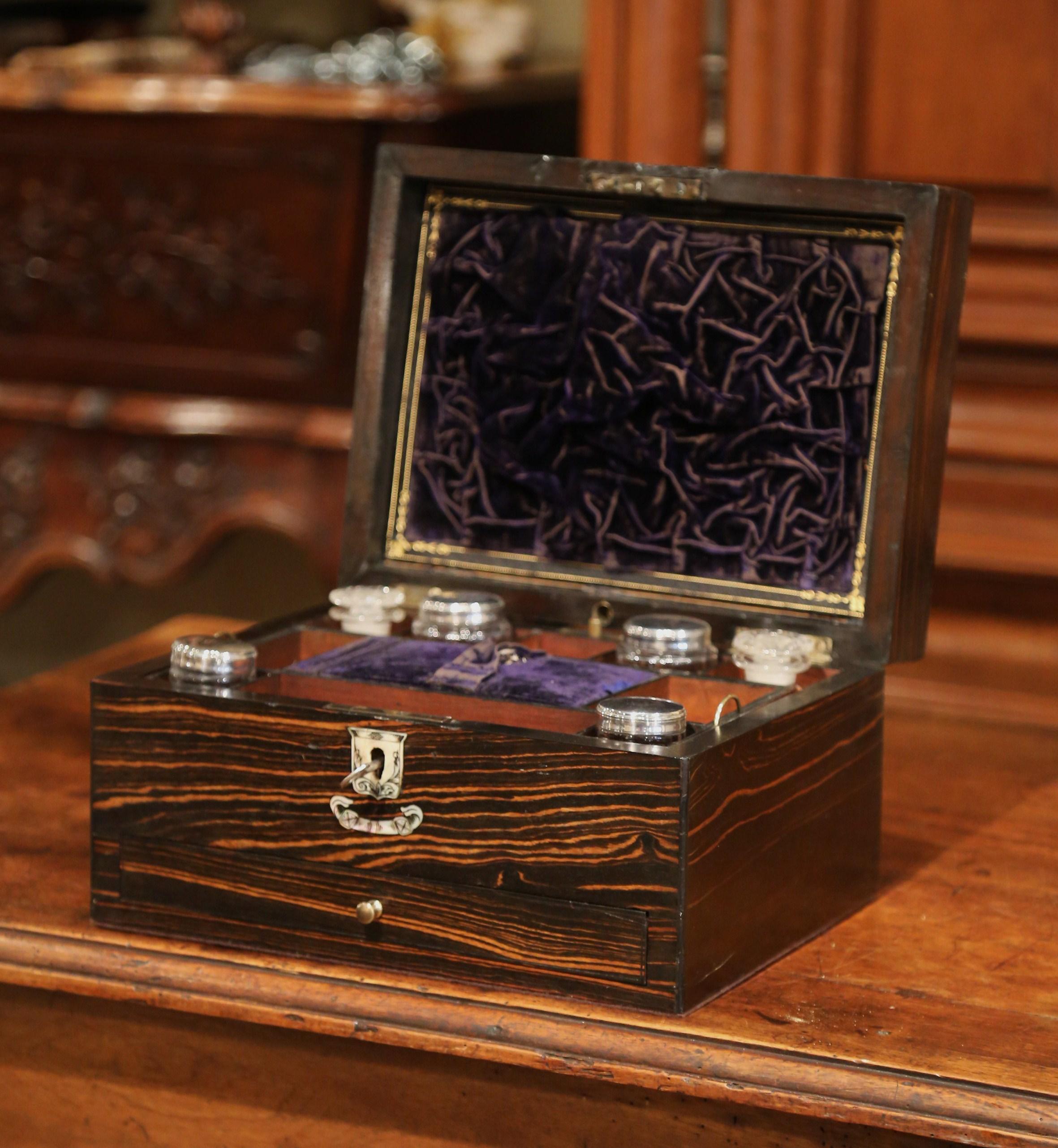 This beautiful, antique jewelry box set was crafted in France, circa 1870. The box has a mother of pearl crest on the top and front, and reveals several dividers inside while the compartments are outfitted with silver and glass containers. The