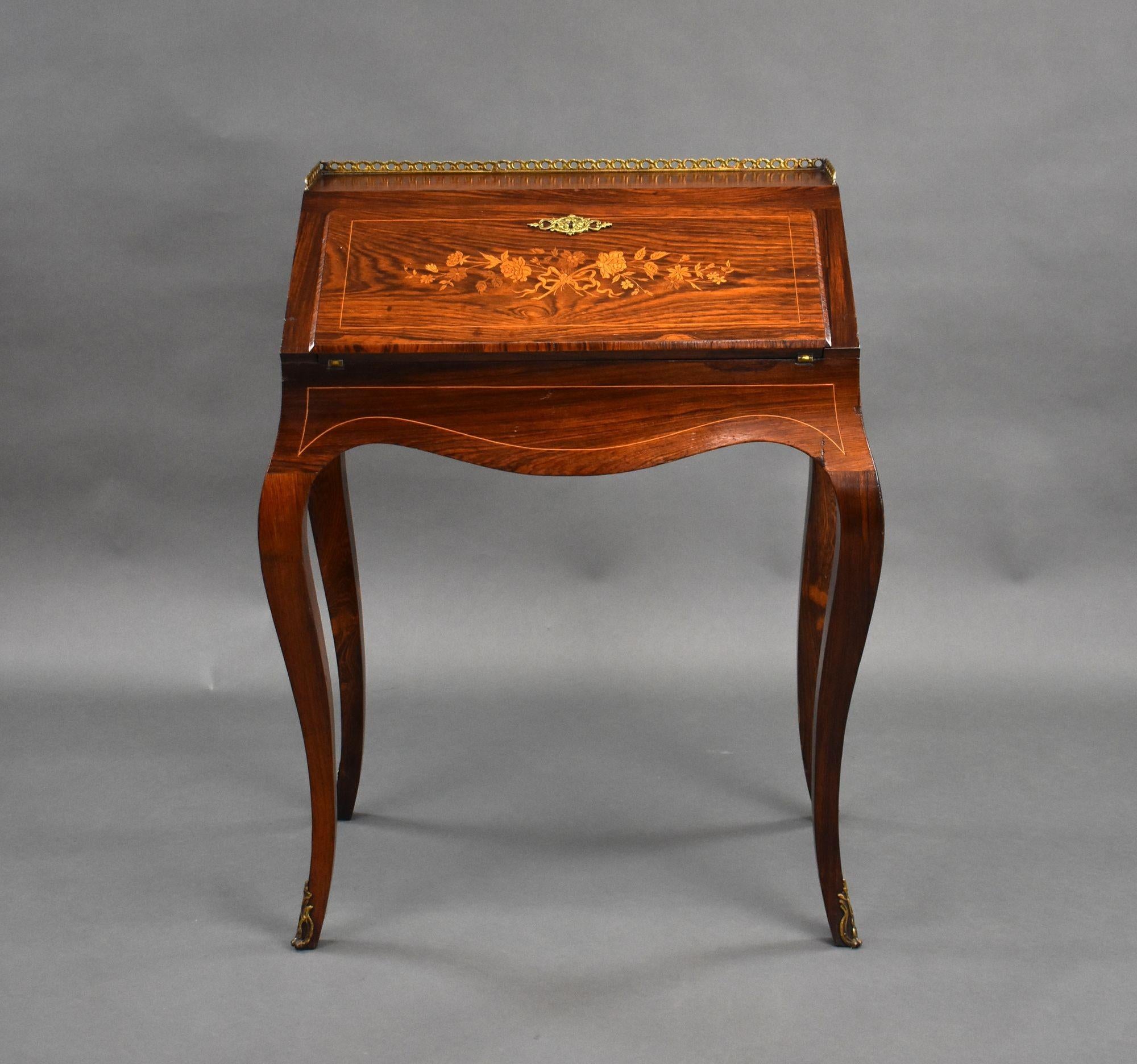 For sale is a good quality French rosewood Bureau De Dame. The top of the bureau has a nice brass gallery above a fall front, decoratively inlaid with marquetry, opening to reveal a fitted interior consisting of two drawers, a baise writing surface