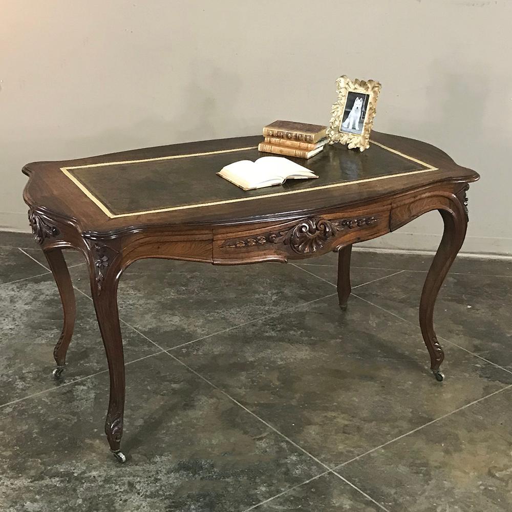 19th century French rosewood leather top desk, writing table features hand-sculpted excellence on each of the four scrolled aprons, all supported by graceful cabriole legs with complementary carving. It is carved and beautifully finished on all four