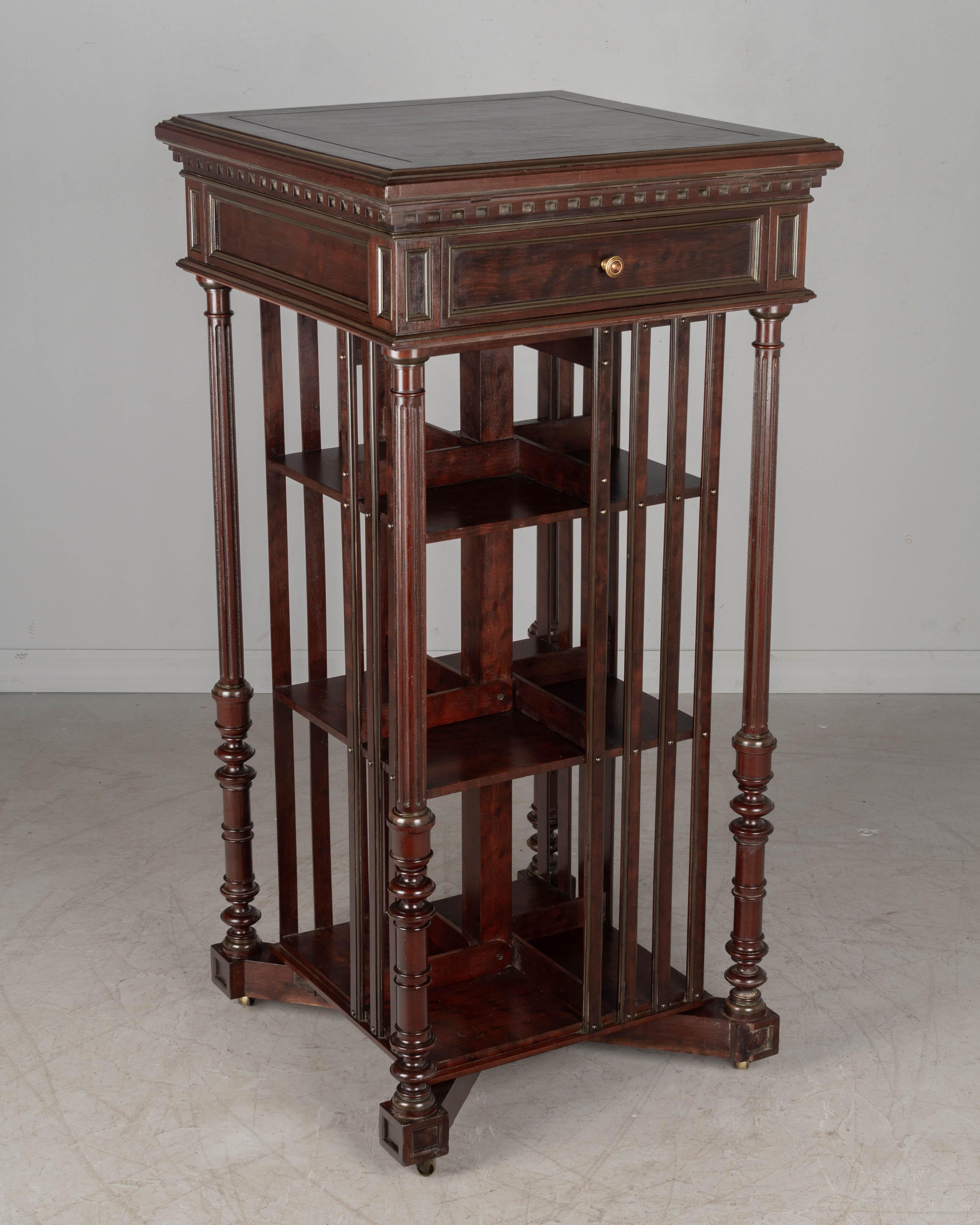 A French bibliotheque tournante, or revolving bookcase made by Terquem, Paris. Made of solid mahogany with brass inlay trim, this bookcase has three shelves with adjustable dividers to accommodate books of various sizes. The top is an adjustable