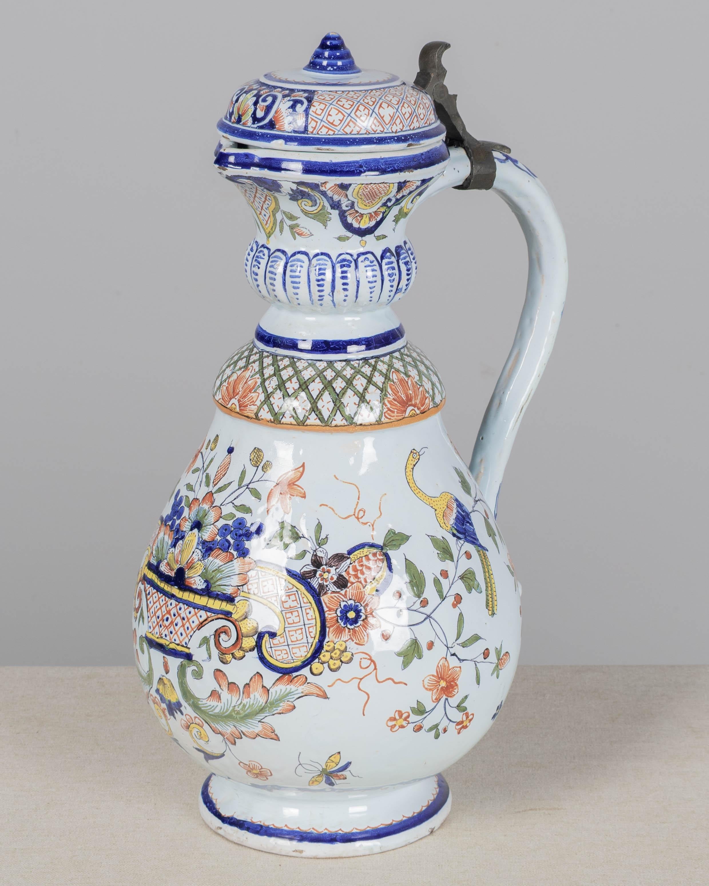 Pichet en faïence de Rouen du 19e siècle avec couvercle à charnière. Design/One peint à la main avec des motifs floraux, feuillus et géométriques en bleu, orange, vert et jaune. Influencée par la porcelaine d'Asie de l'Est, cette décoration
