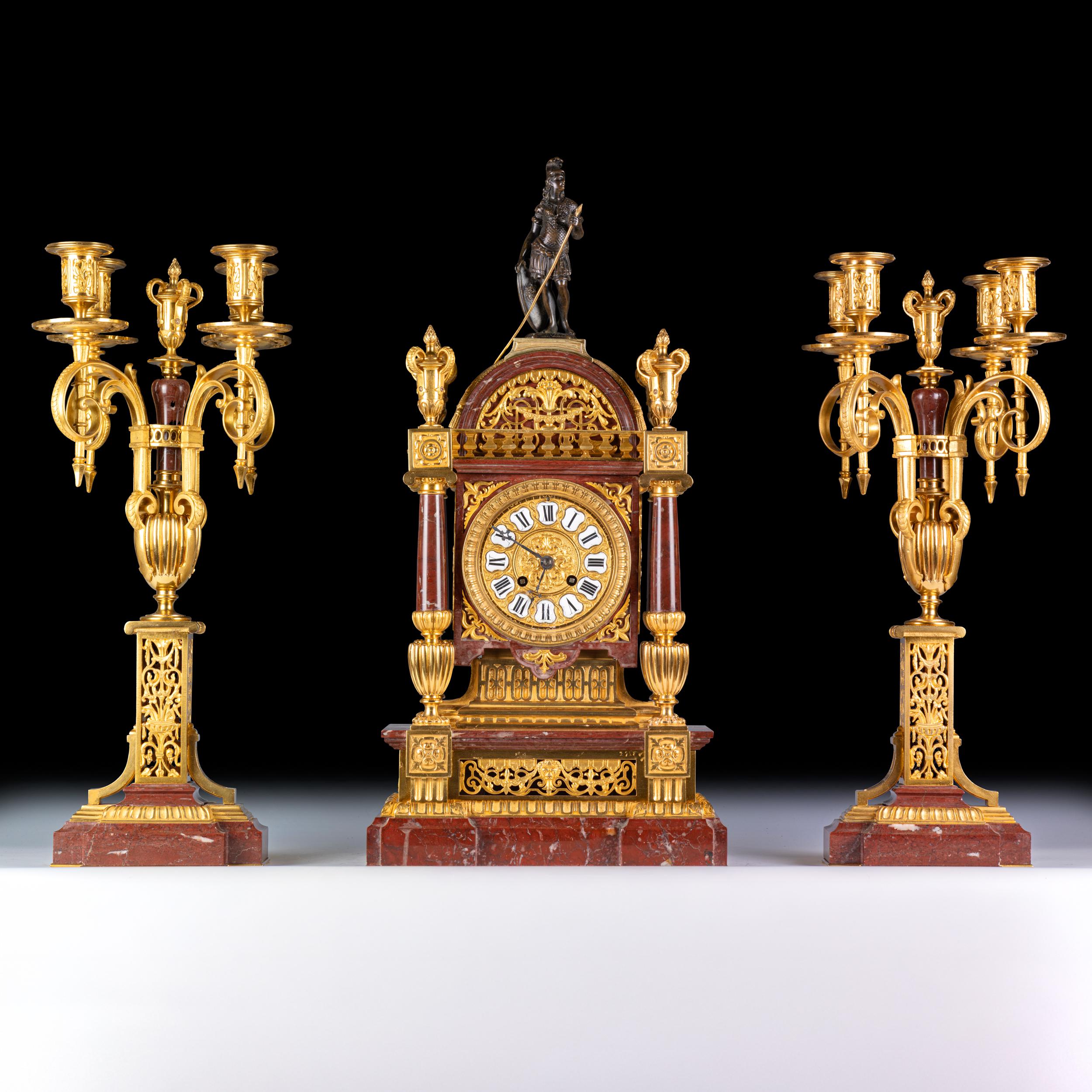 Garniture d'horloge française du XIXe siècle, l'horloge avec un soldat en bronze surmonté d'un sommet en dôme avec des fleurons en urne sur quatre piliers en marbre rouge, sur une base décorée percée sur une plate-forme rectangulaire en forme avec