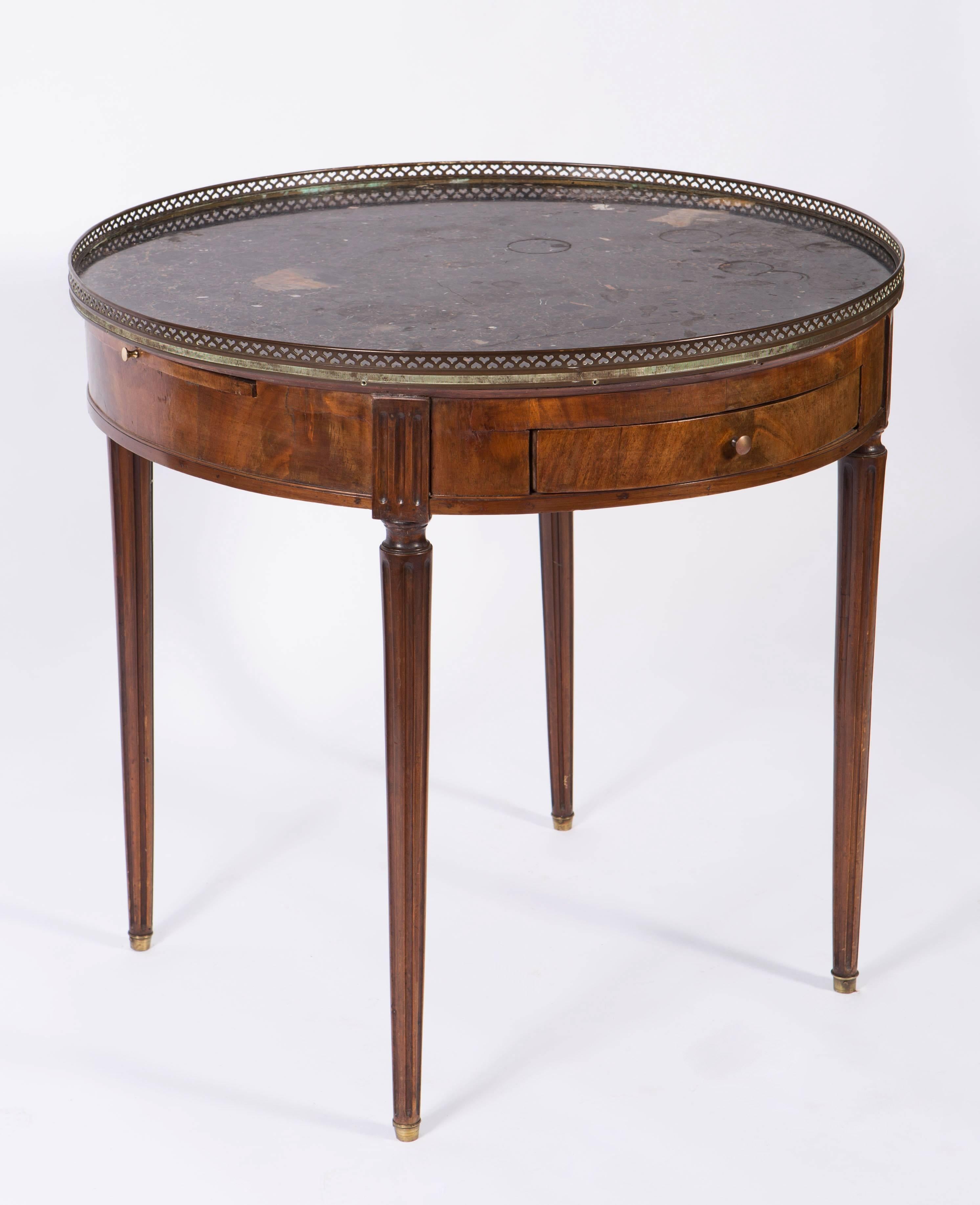 19th century French round mahogany side table with marble top with brass gallery. The round table has two drawers, one on each side and two candle slides, one on each side as well. The marble has a crack that does not distract from the piece.  
