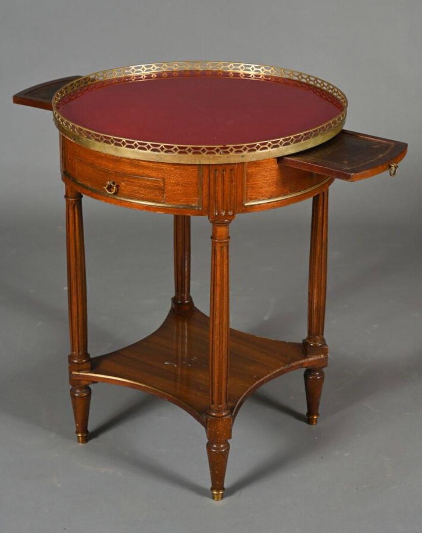 19th Century hand carved side table in veneered wood, opening with two drawers and two belt pulls, resting on fluted uprights joined by a brace shelf, finished with tapered legs. Red glass top surrounded by an openwork brass gallery.  Louis XVI