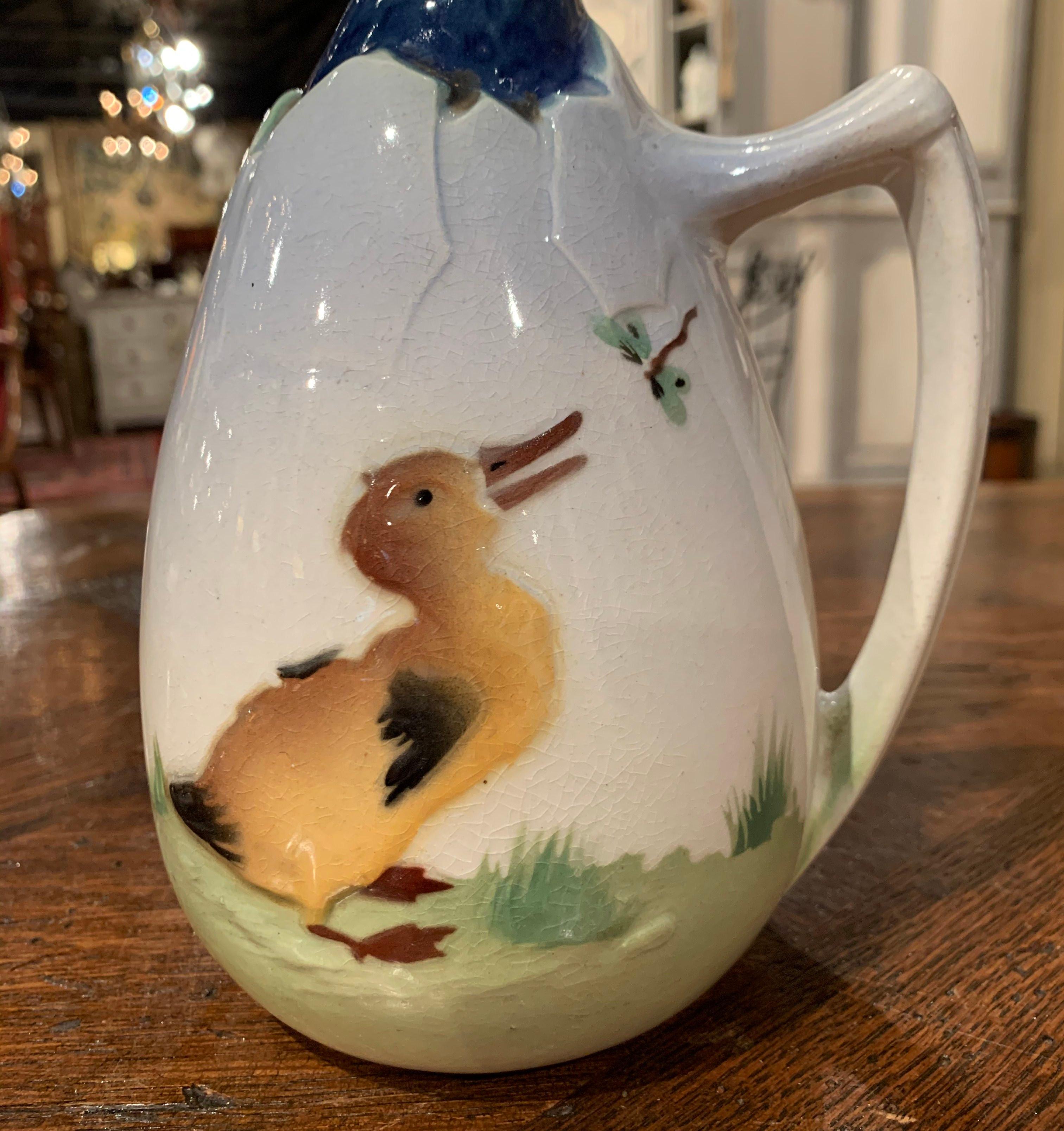 This colorful Majolica water pitcher was sculpted in Saint Clement, France, circa 1890. The charming ceramic jug with spout thru the mouth, is in the shape of a colorful young duck exciting the egg shell. The pitcher is hand painted with a small