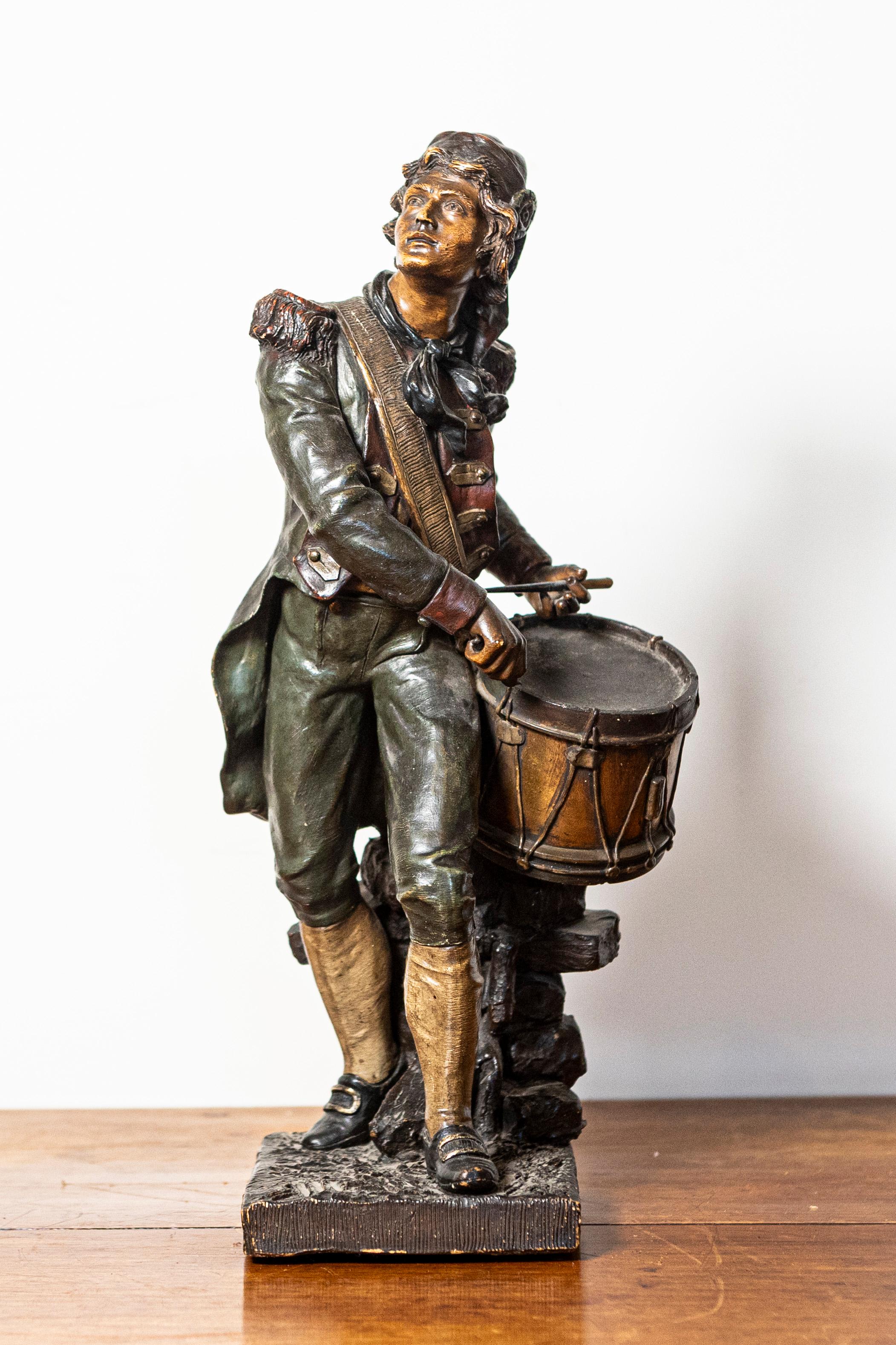 Questa scultura francese del XIX secolo raffigura un giovane batterista, catturato in un momento di intensa concentrazione ed energia. Realizzata in una ricca patina di bronzo, la figura è vestita in abiti militari storici, con un'espressione