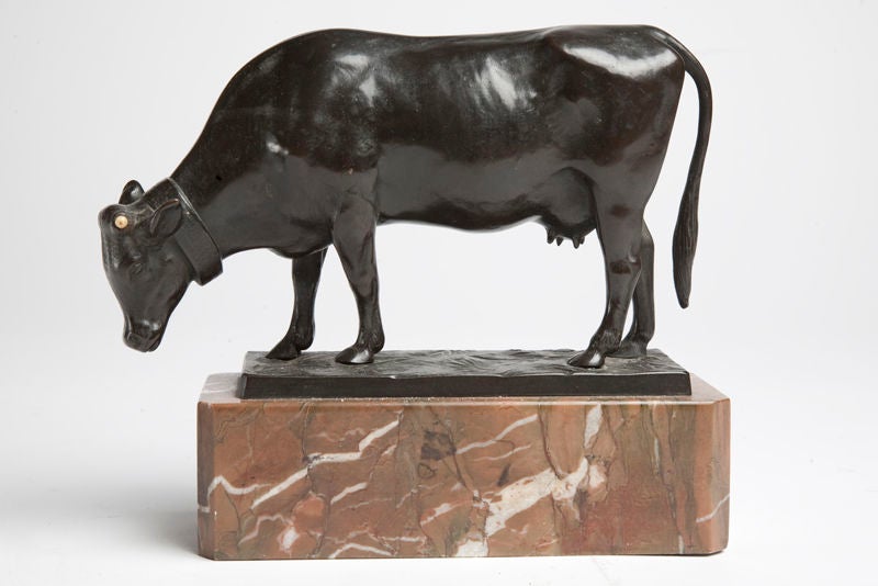 A bronze sculpture, lost wax process, depicting a cow pasturing over the grass, Verona red marble base. Signed Moseritz, France.