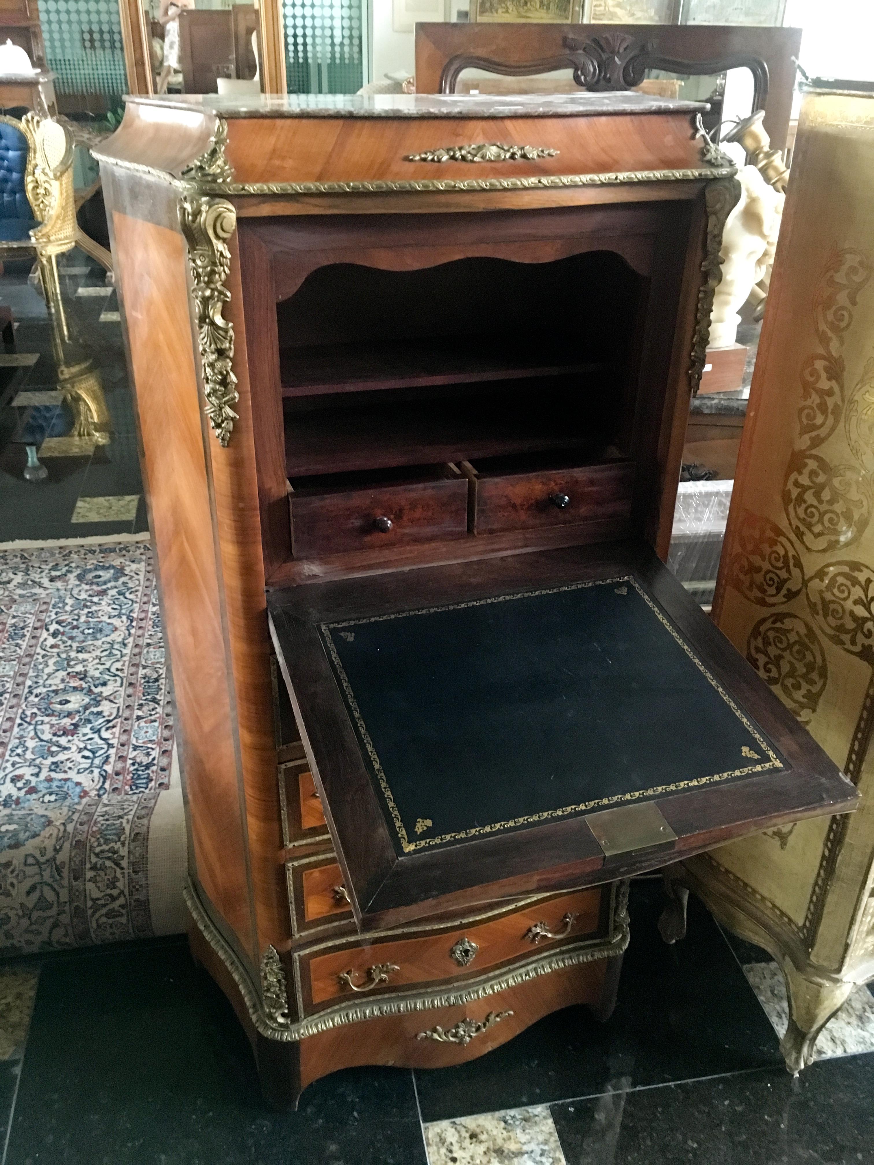 Small secretaire in doucine, curved on three sides, in veneer of precious wood inlaid in leaves in entourages of nets. It opens with four large drawers, a flap revealing two small drawers and shelves. Beautiful bronze trim and thin red marble