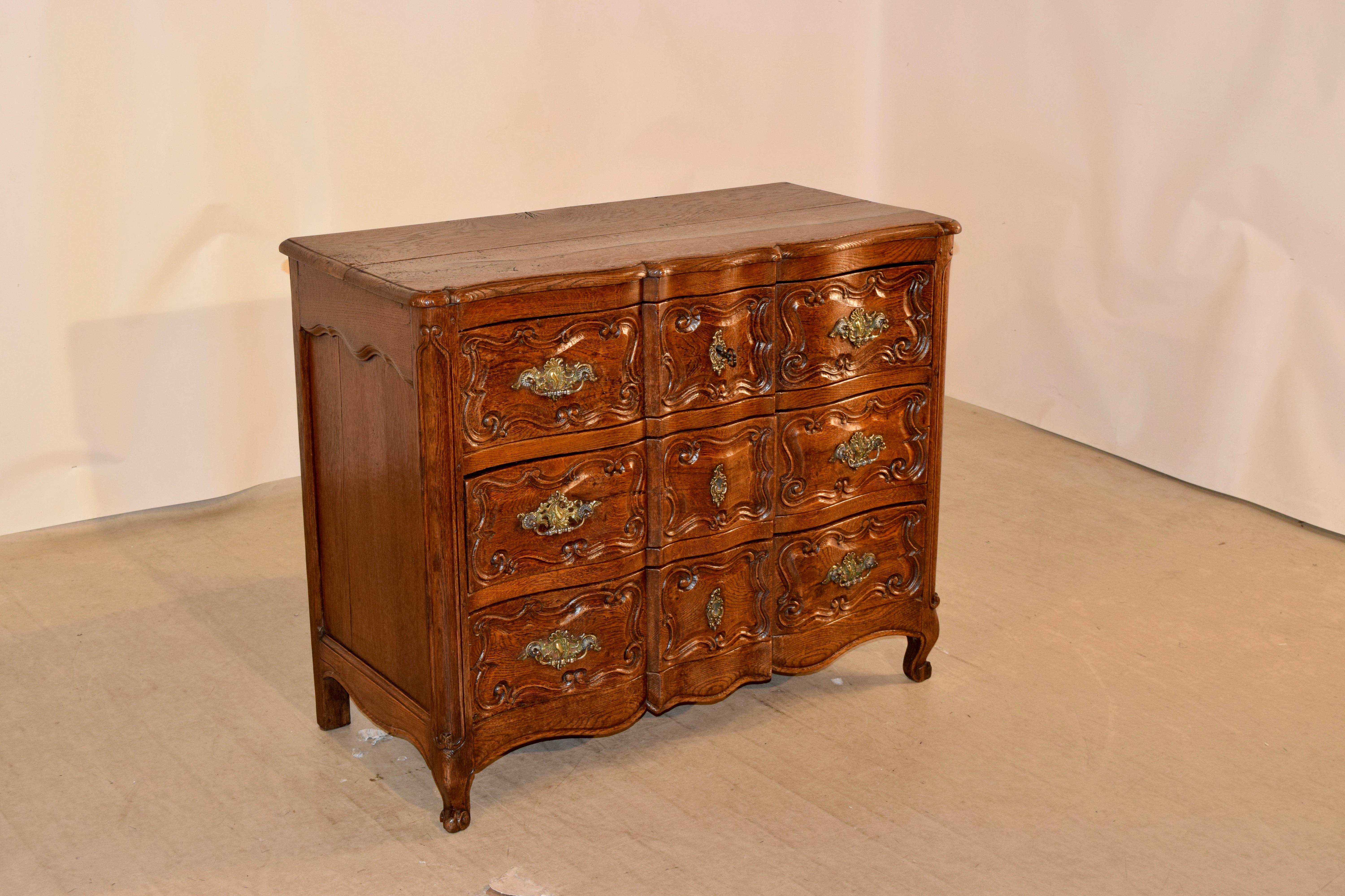 19th century oak chest from France with a serpentine front. The top has a beveled and scalloped edge, following down to hand shaped and paneled sides and three drawers in the front. The drawer fronts are hand paneled and shaped and have what appears