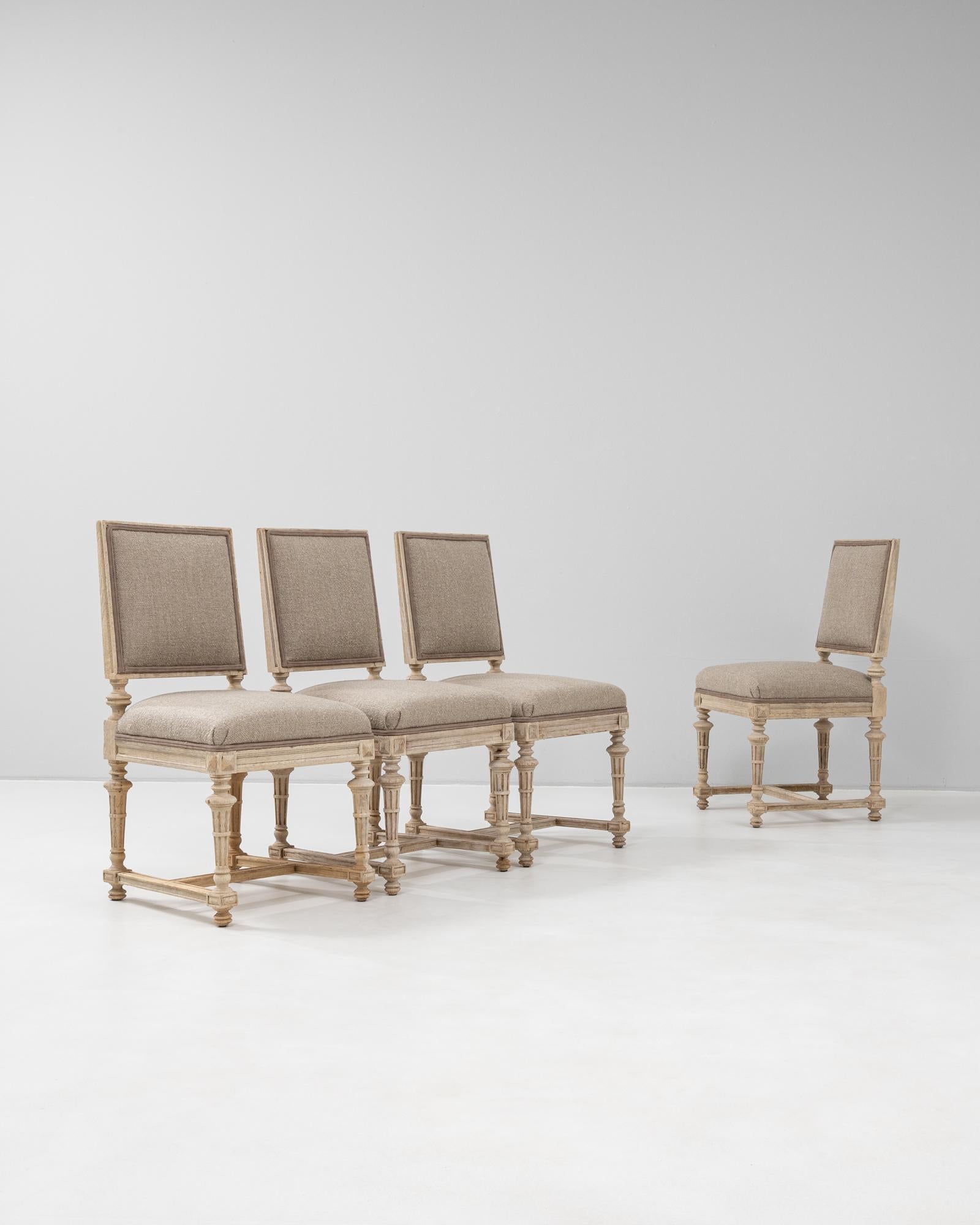 This 19th century French set of four dining chairs embodies classic Louis XVI style, with square upholstered backs and seats framed by finely carved woodwork. The light patina of the wood enhances the neoclassical design, featuring fluted legs,