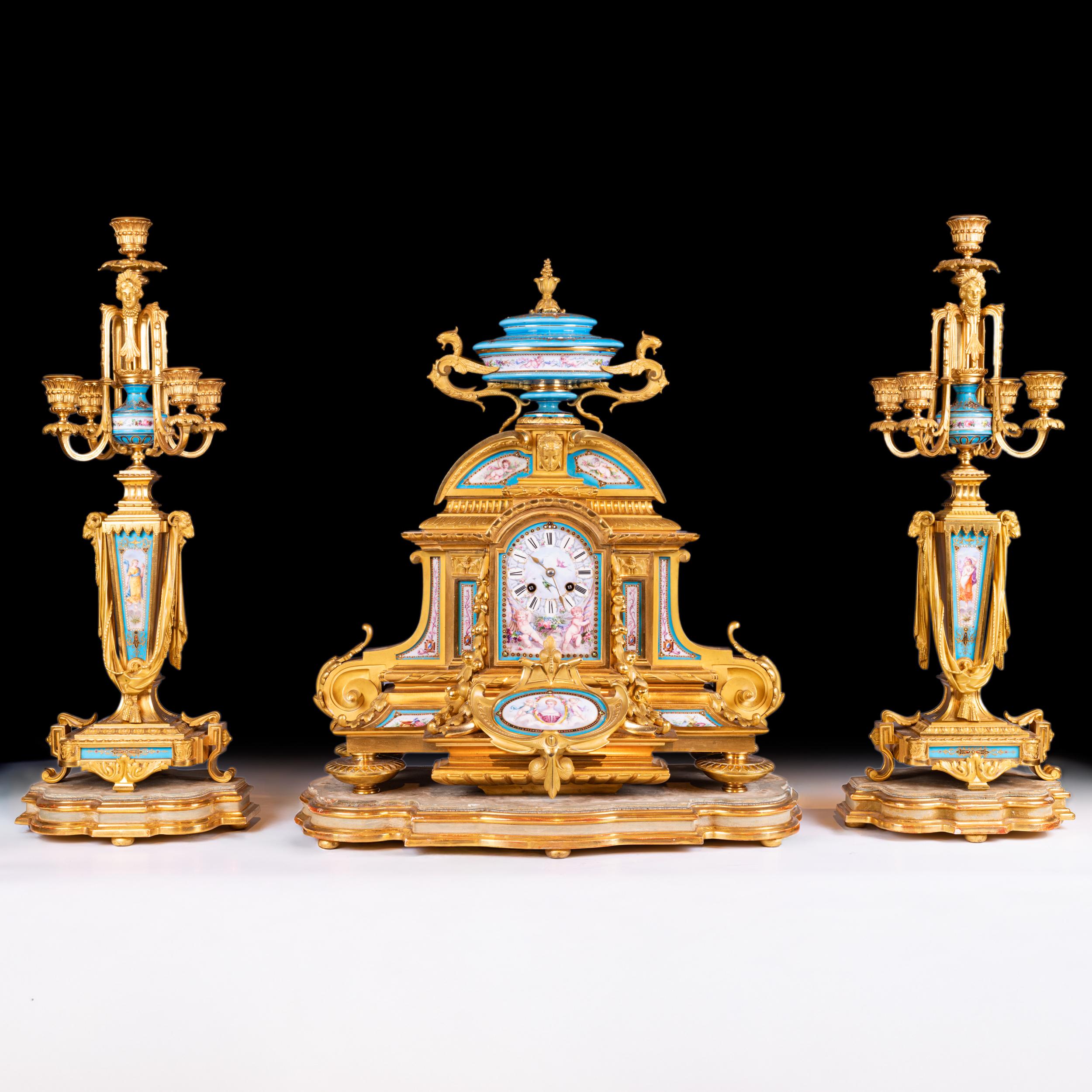 A Fine 19th Century French Sevres-Style Porcelain and Gilt Bronze Clock Garniture. Comprising a central mantel clock and a pair of five-light candelabra, each richly decorated with hand-painted panels in the Sevres manner depicting classical