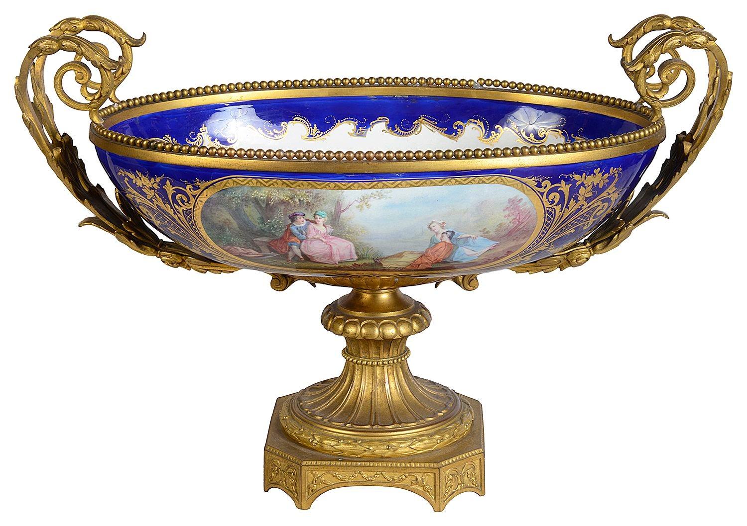 Un portavaso in porcellana francese di Sèvres della fine del XIX secolo, di buona qualità, con maniglie, modanature e base in ormolu dorate e a volute. Il fondo blu cobalto con riflessi dorati, contiene pannelli dipinti a mano che raffigurano una