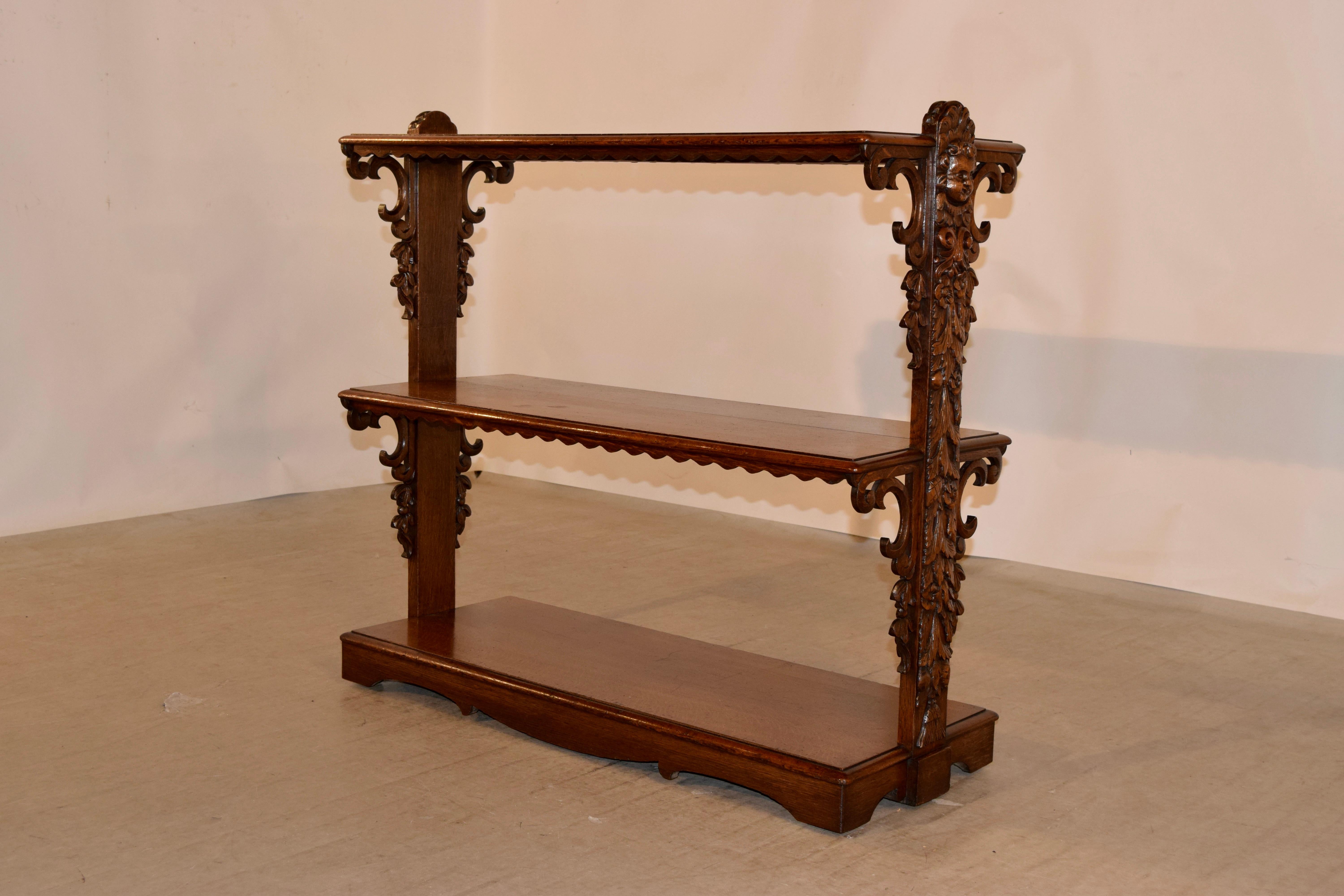 19th century oak shelf from France with three shelves, all with beveled edges and scalloped aprons. The shelves are joined on the sides by wonderfully hand carved central supports and gorgeous hand carved brackets. The base is scalloped as well for