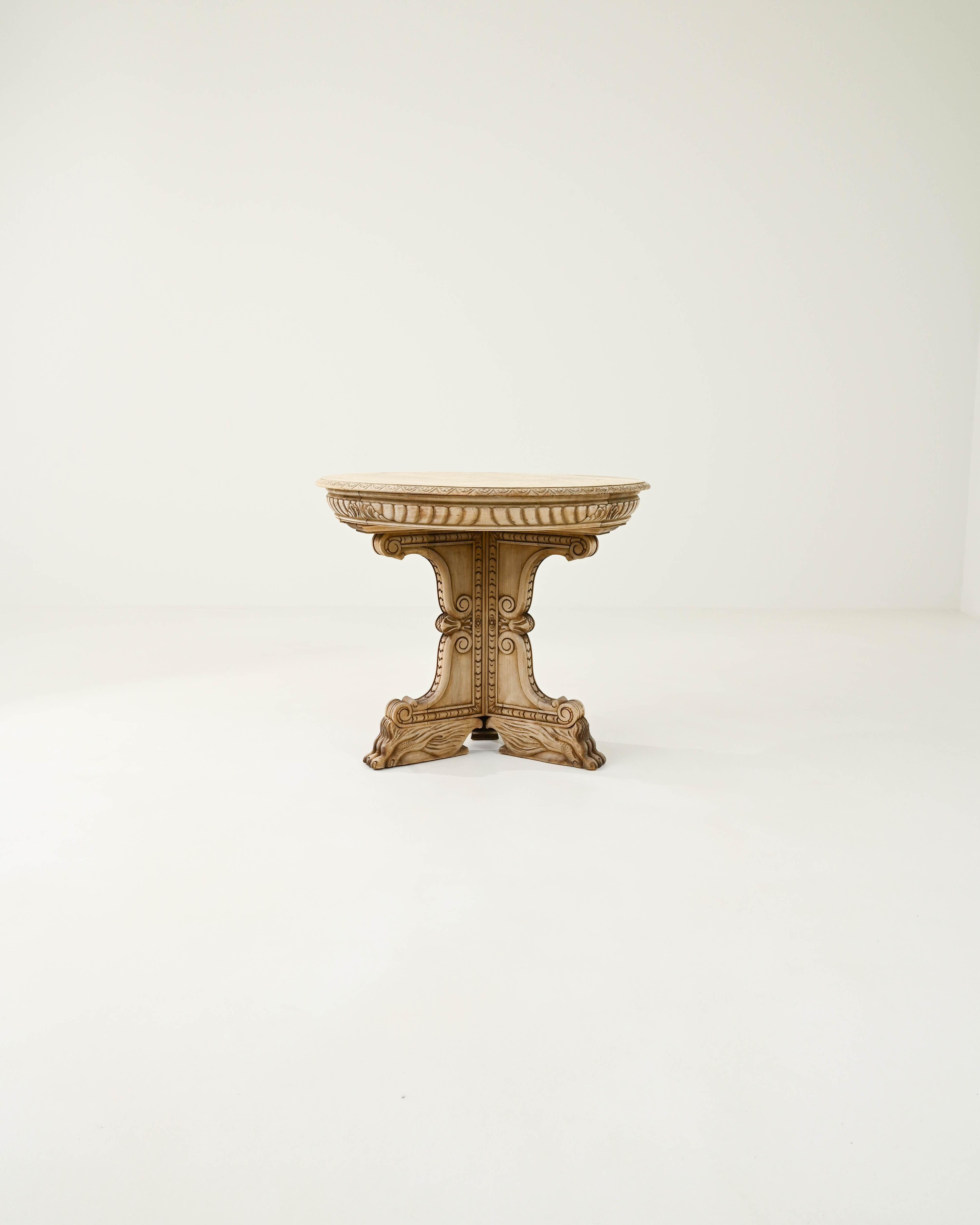 A hardwood table from 19th century France. The circular shaped side table is adorned with elaborate carvings, rendered in typical beech wood. A distinctive Northern French visual language references baroque shapes, from classical architecture and