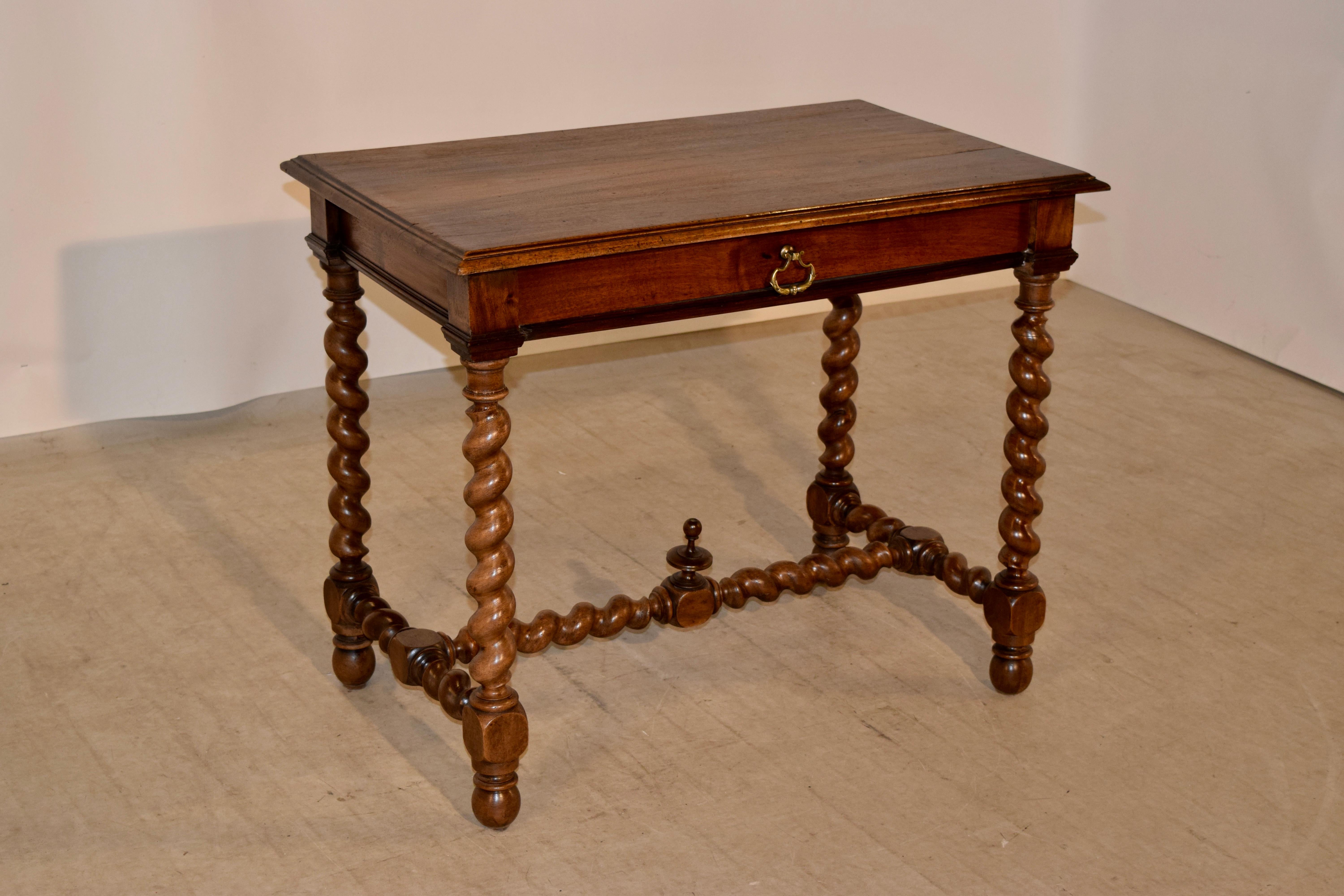 19th century walnut side table from France with a beveled and molded edge around the top, following down to a simple apron which contains a single drawer in the front of the piece. The table is supported on hand turned barley twist legs and matching
