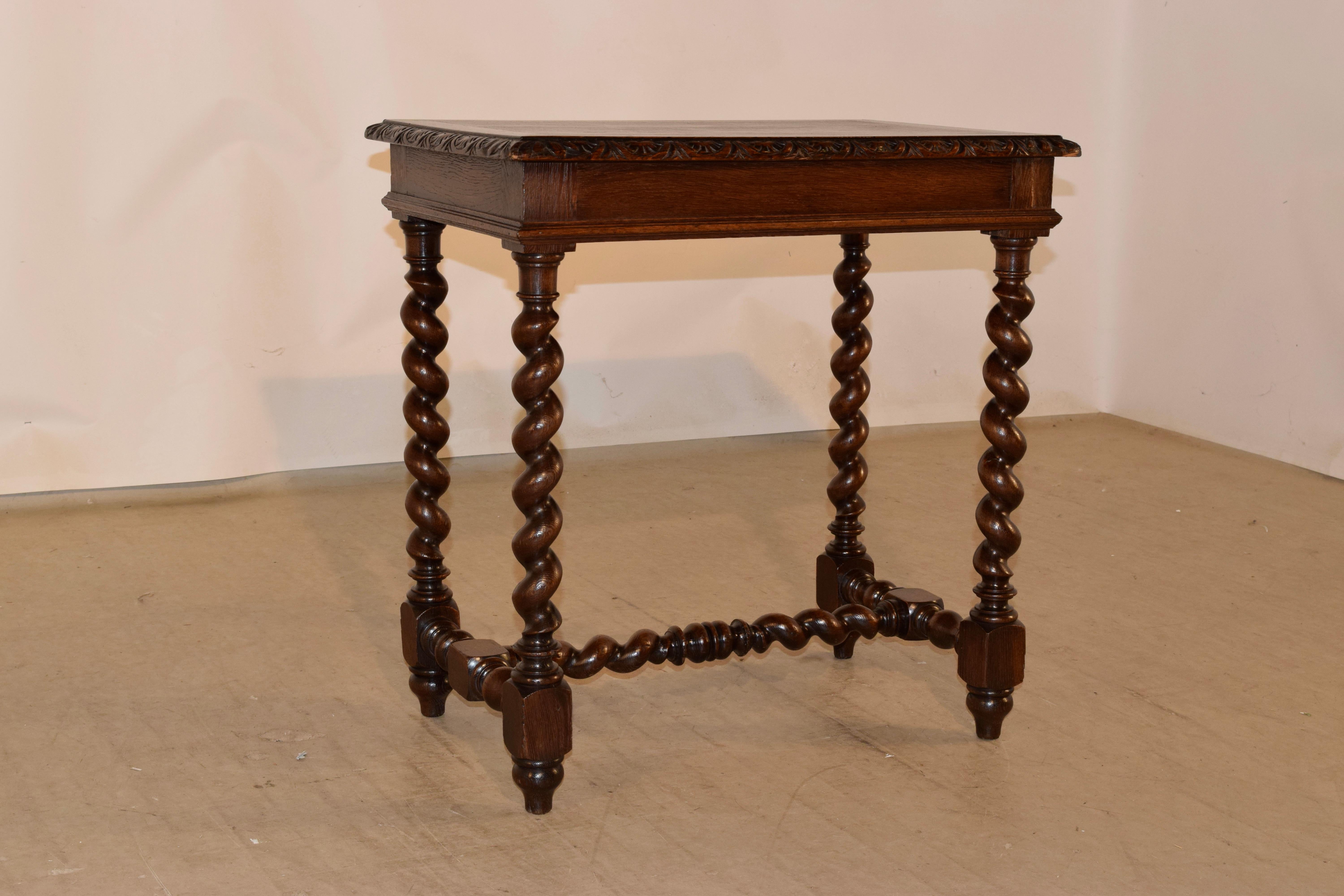 19th century oak side table from France made from oak. The top is banded and has a beveled and carved decorated edge around the top, following down to a simple apron, which has a molded edge and is supported on hand turned barley twist legs, joined