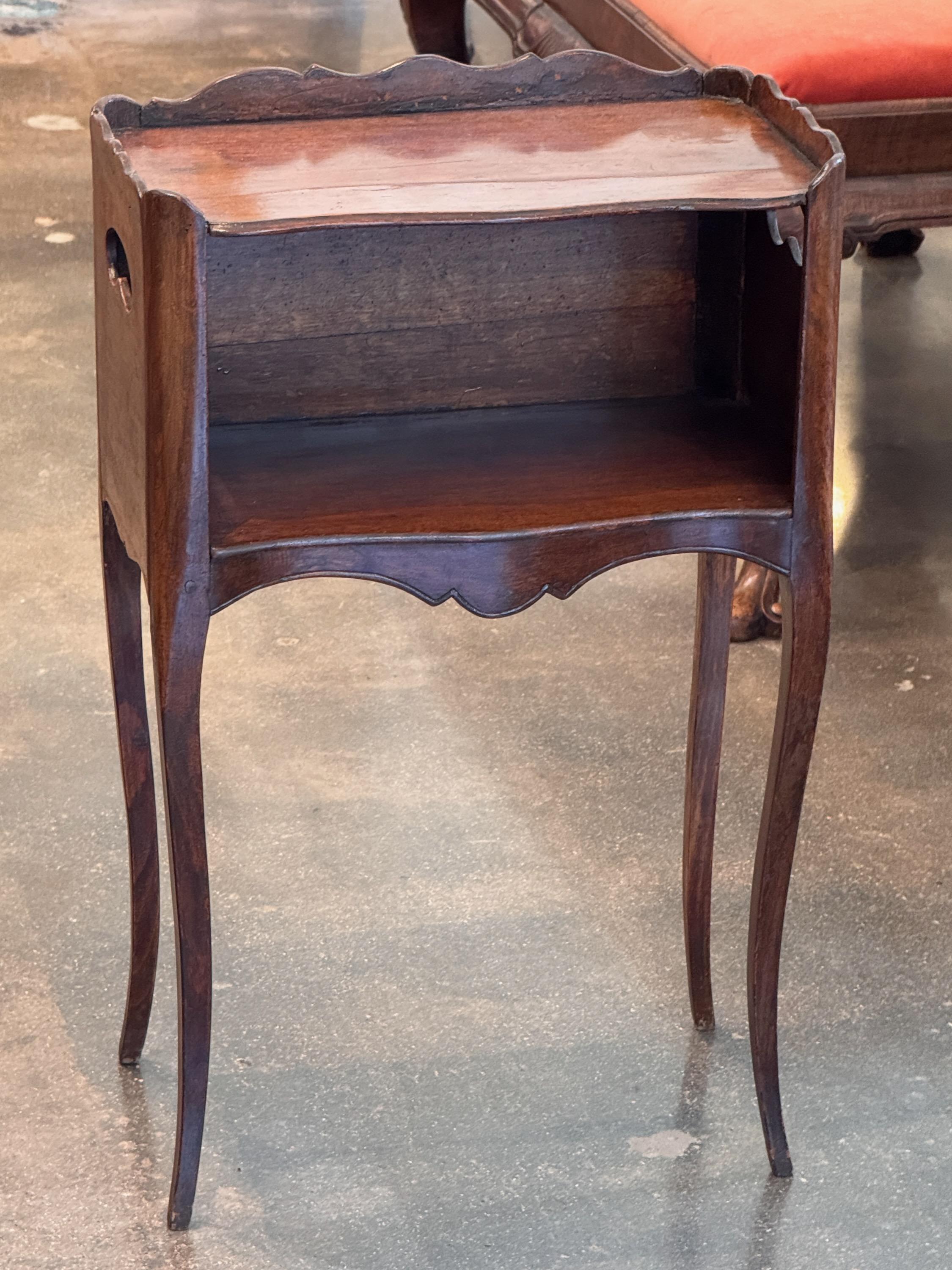 Table d'appoint française du 19e siècle avec un meuble ouvert, un tablier façonné et un plateau à galerie festonné. Les pieds en cabriole et les lignes courbes sur l'ensemble de la pièce lui confèrent une silhouette douce et fluide. Les découpes