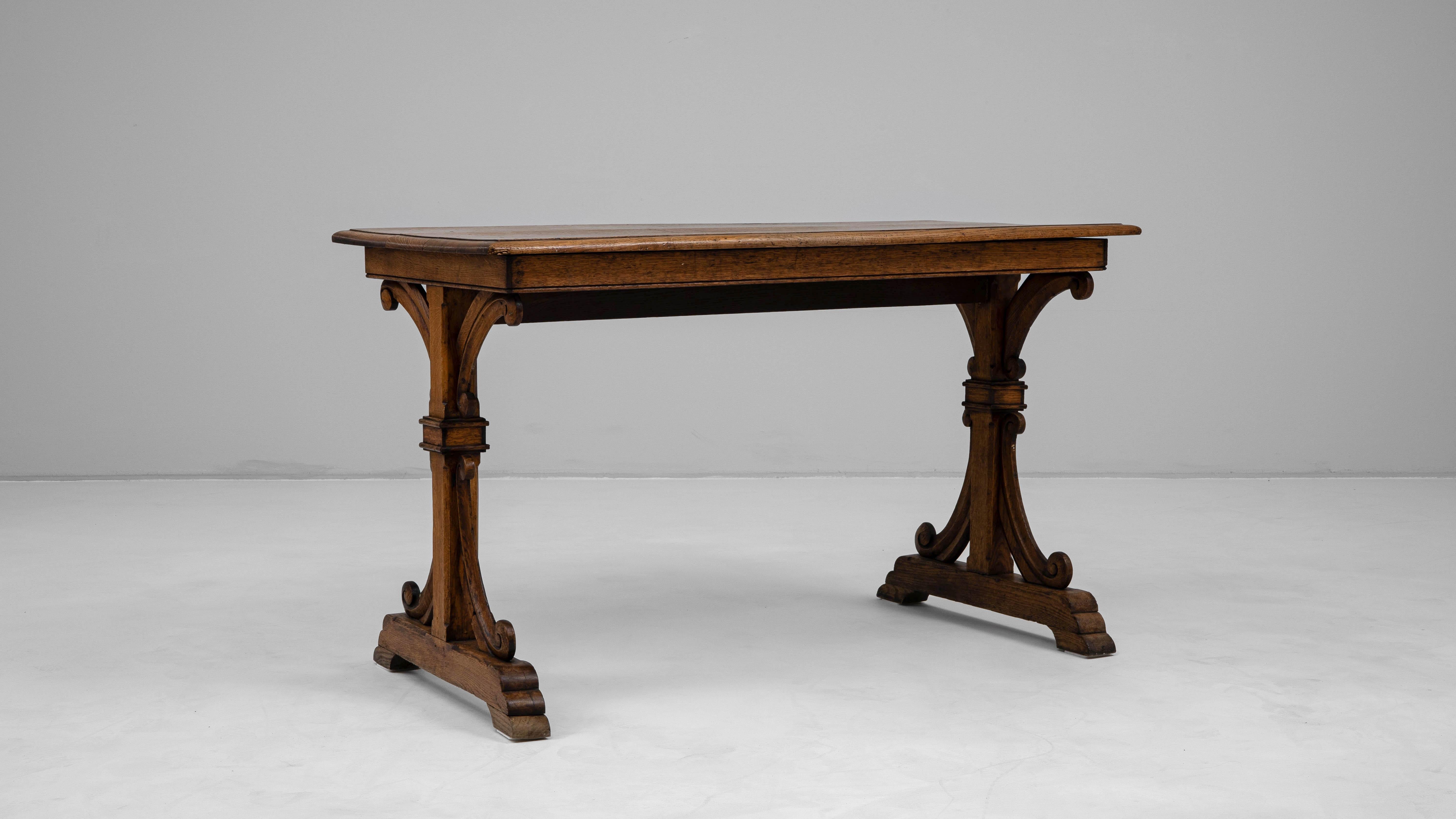 This 19th Century French side table showcases exceptional craftsmanship and refined proportions. Crafted from solid wood, it features an elegant trestle base with carved scroll details and a rectangular top displaying a beautifully aged original