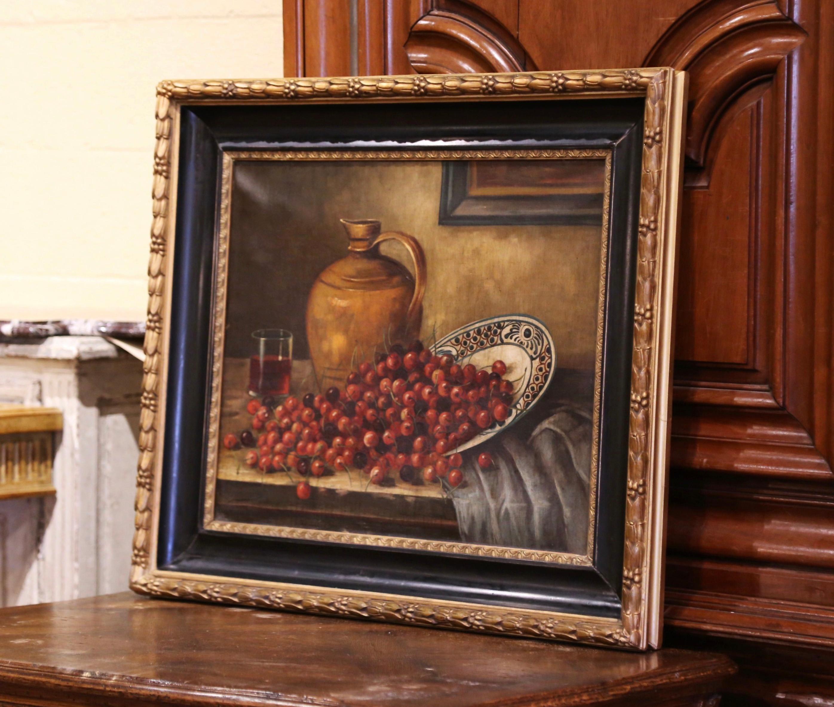 Peinte à la main en France vers 1880 et placée dans son cadre d'origine sculpté en bois doré et noirci, cette grande œuvre d'art représente une nature morte de table avec des raisins s'écoulant d'une assiette en faïence, avec une cruche à vin en