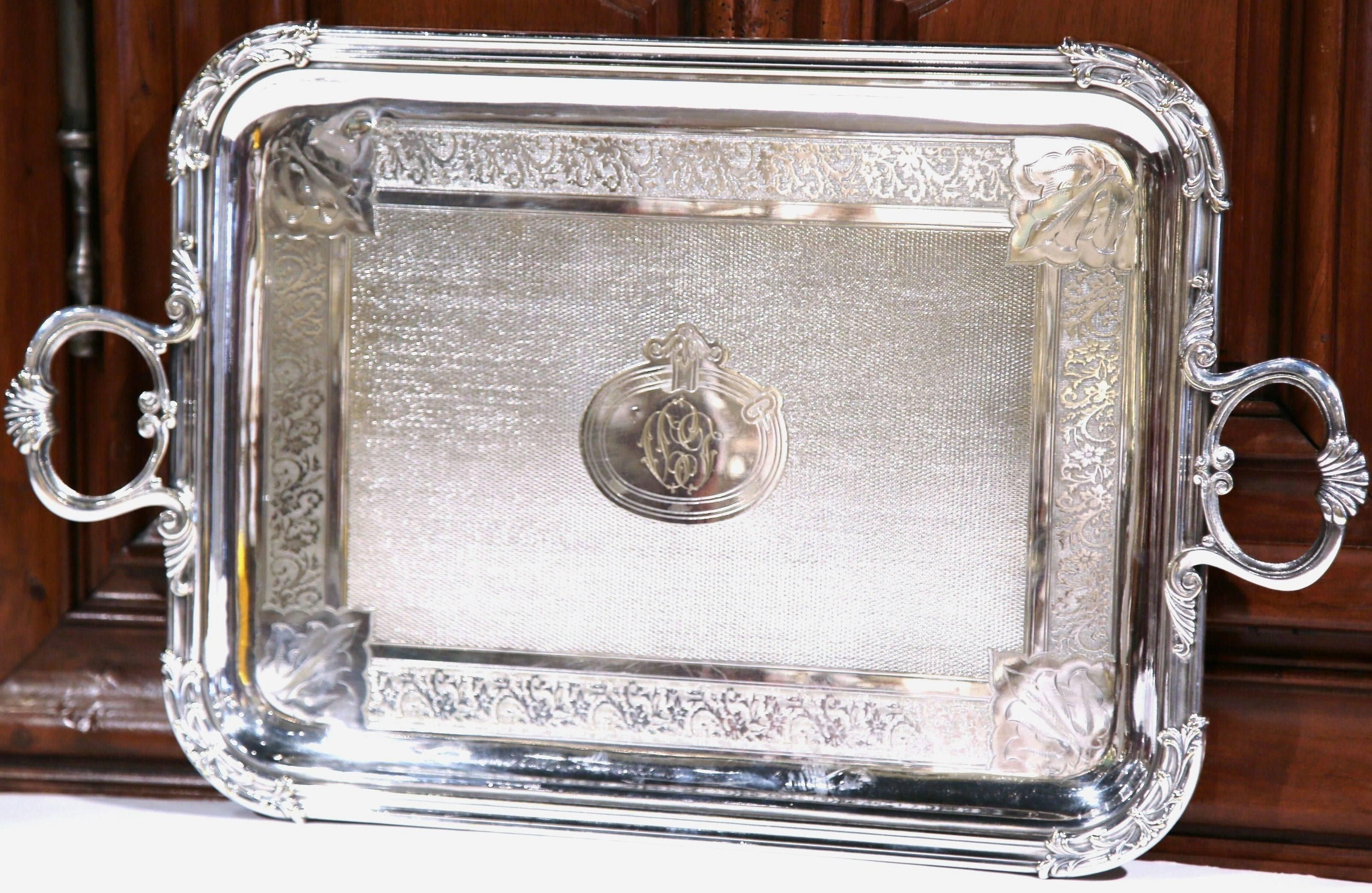 This elegant antique silver plated tray was created in Paris, France, circa 1894. The rectangular serving piece has two side handles, repousse motifs of leaf motif in each corner, a center monogram, and intricate engraved designs on the surface. The