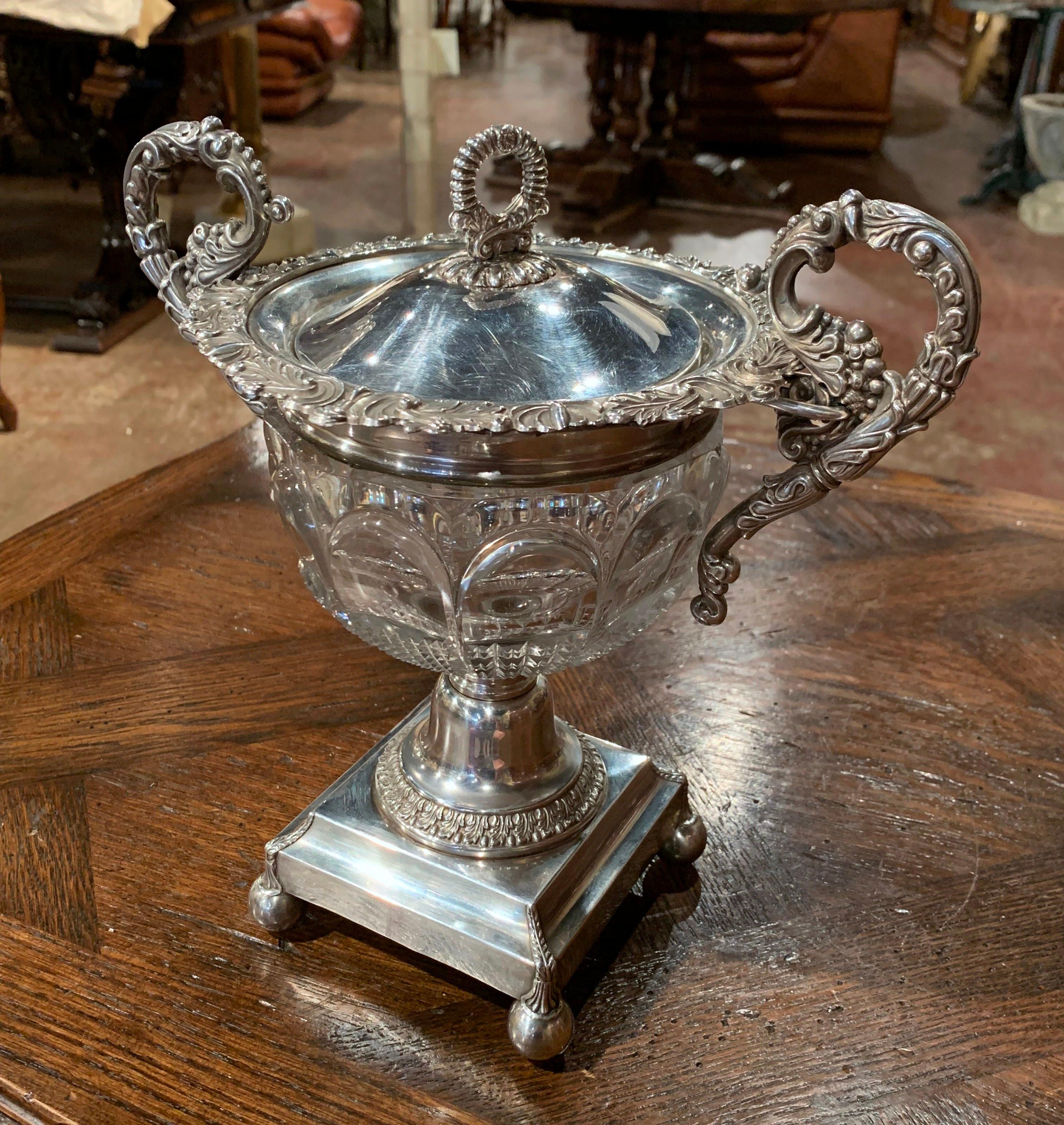 This elegant and large antique sugar bowl was crafted in France, circa 1870.; made of cut crystal and silver plated over copper, the dish sits on a square base over round feet. It features two intricate handles decorated with leaf and fruit motifs,