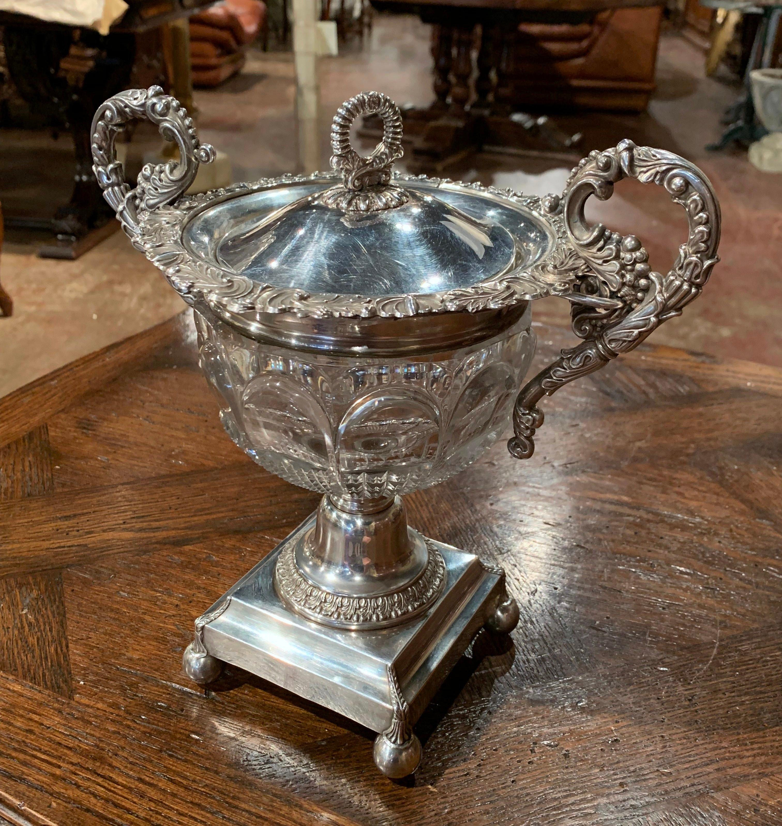 This elegant and large antique sugar bowl was crafted in France, circa 1870.; made of cut crystal and silver plated over copper, the dish sits on a square base over round feet. It features two intricate handles decorated with leaf and fruit motifs,