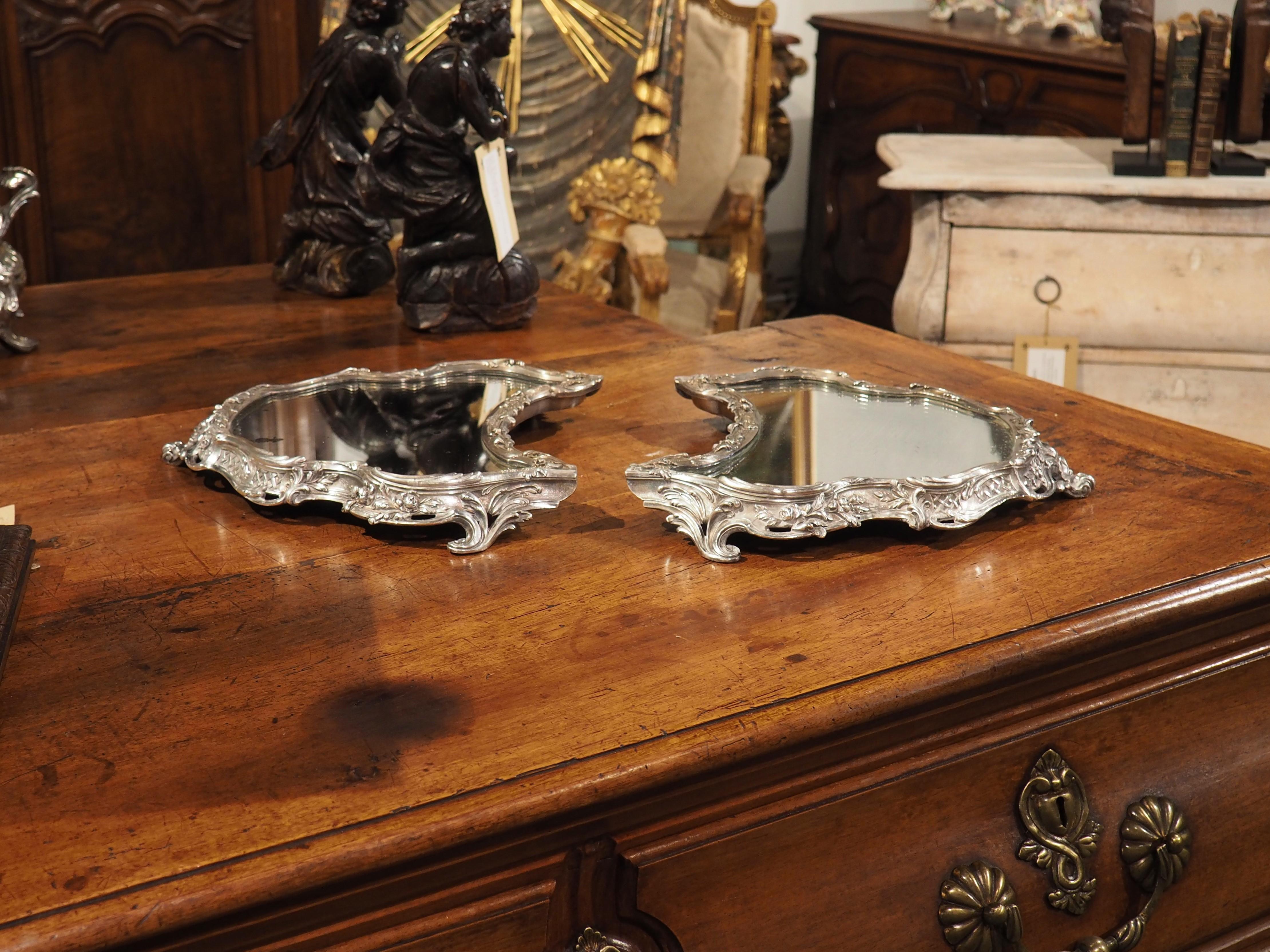 Entrez dans le monde de l'exquise France du 19e siècle avec un surtout de table en bronze argenté à deux pièces. Ces magnifiques pièces sont ornées de miroirs de grande forme et sont entourées de motifs floraux et feuillus complexes. Le savoir-faire