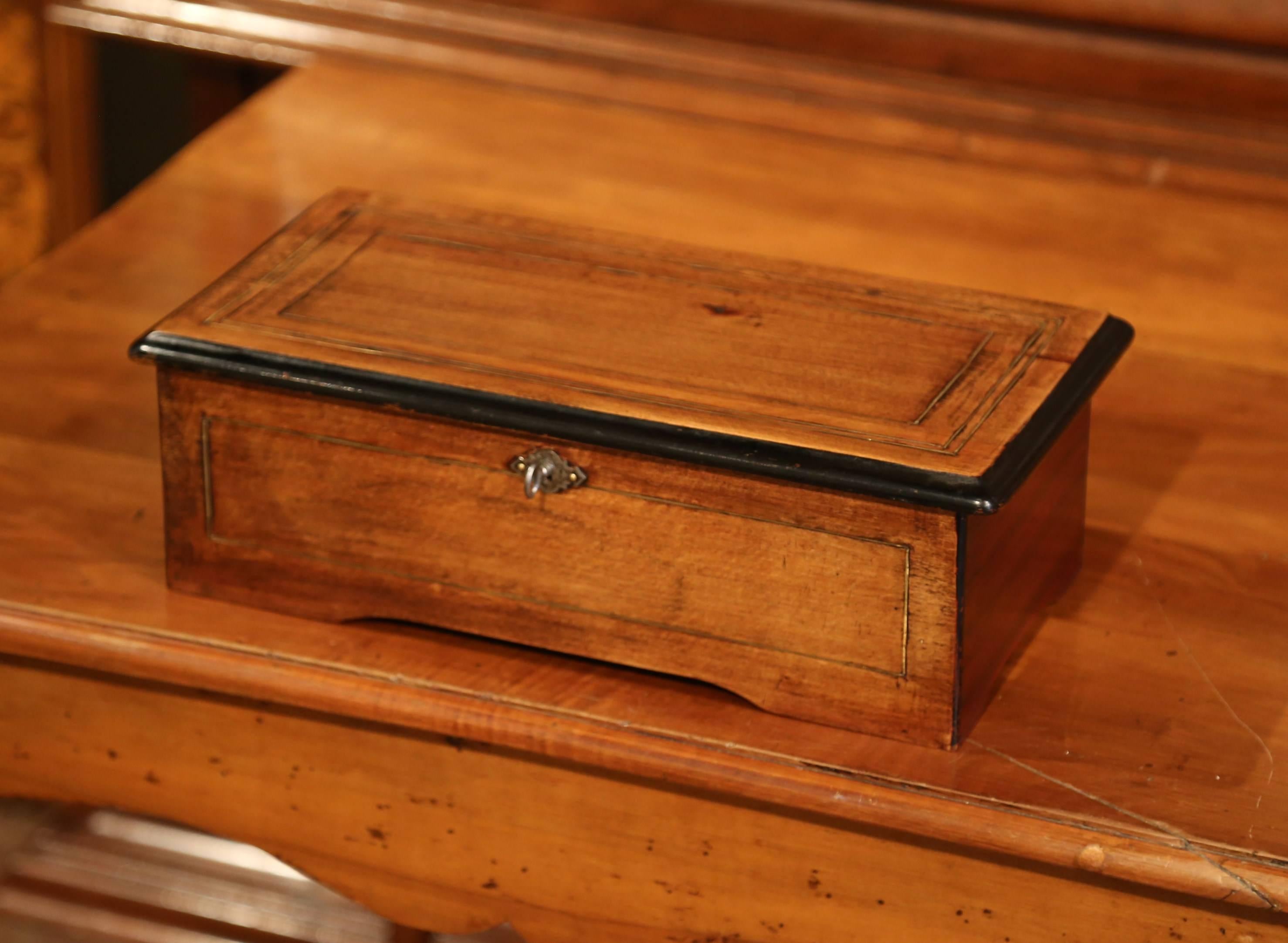 This beautiful, antique music box was crafted in France, circa 1860. The walnut music box has an inlay band and black border, which features six different airs. The hinged lid opens to reveal a cylinder with a comb under a small glass shelf. Inside
