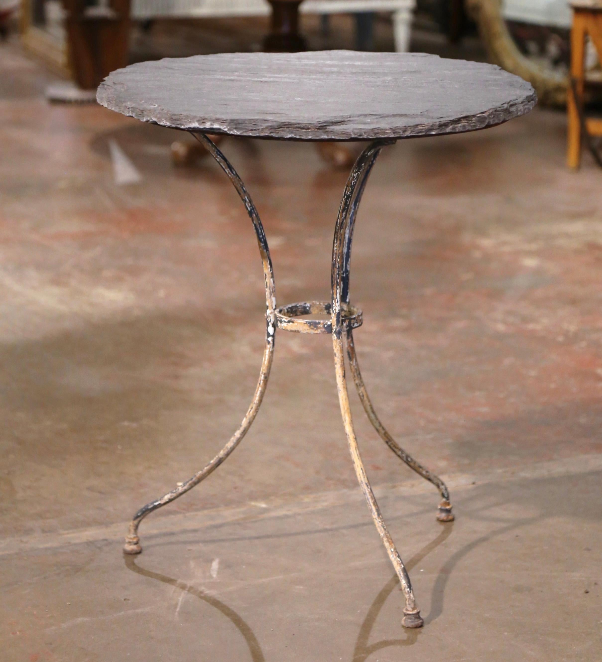 Decorate a patio or covered porch with this elegant antique bistrot table. Crafted in France circa 1870, the cast iron table sits on three scroll legs connected with a round center stretcher. The table surface is dressed with a natural finished gray