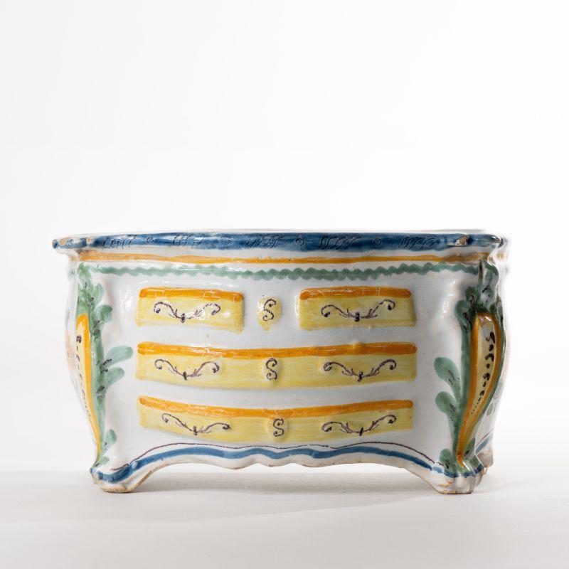 Slip glazed faience bough pot in the form of a bombe chest. The yellow and blue polychrome decoration on white slip glaze delineates three drawers with Rococo drawer pulls.
France, early 1800’s.