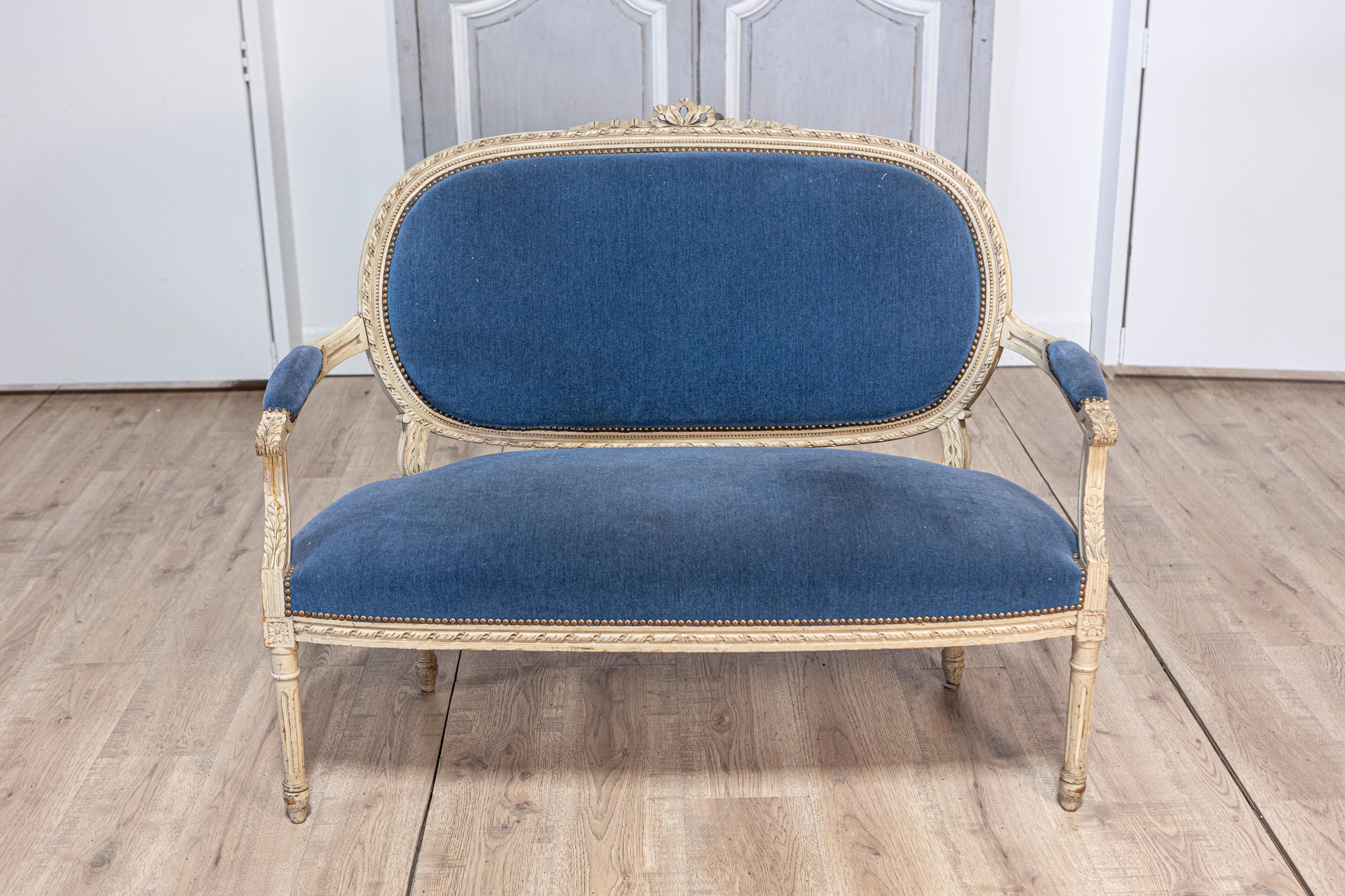 Questo elegante divano in stile Luigi XVI della fine del XIX secolo è realizzato in legno di faggio, verniciato con una morbida finitura anticata che mette in risalto i suoi delicati dettagli intagliati. Poggiato su quattro gambe affusolate e