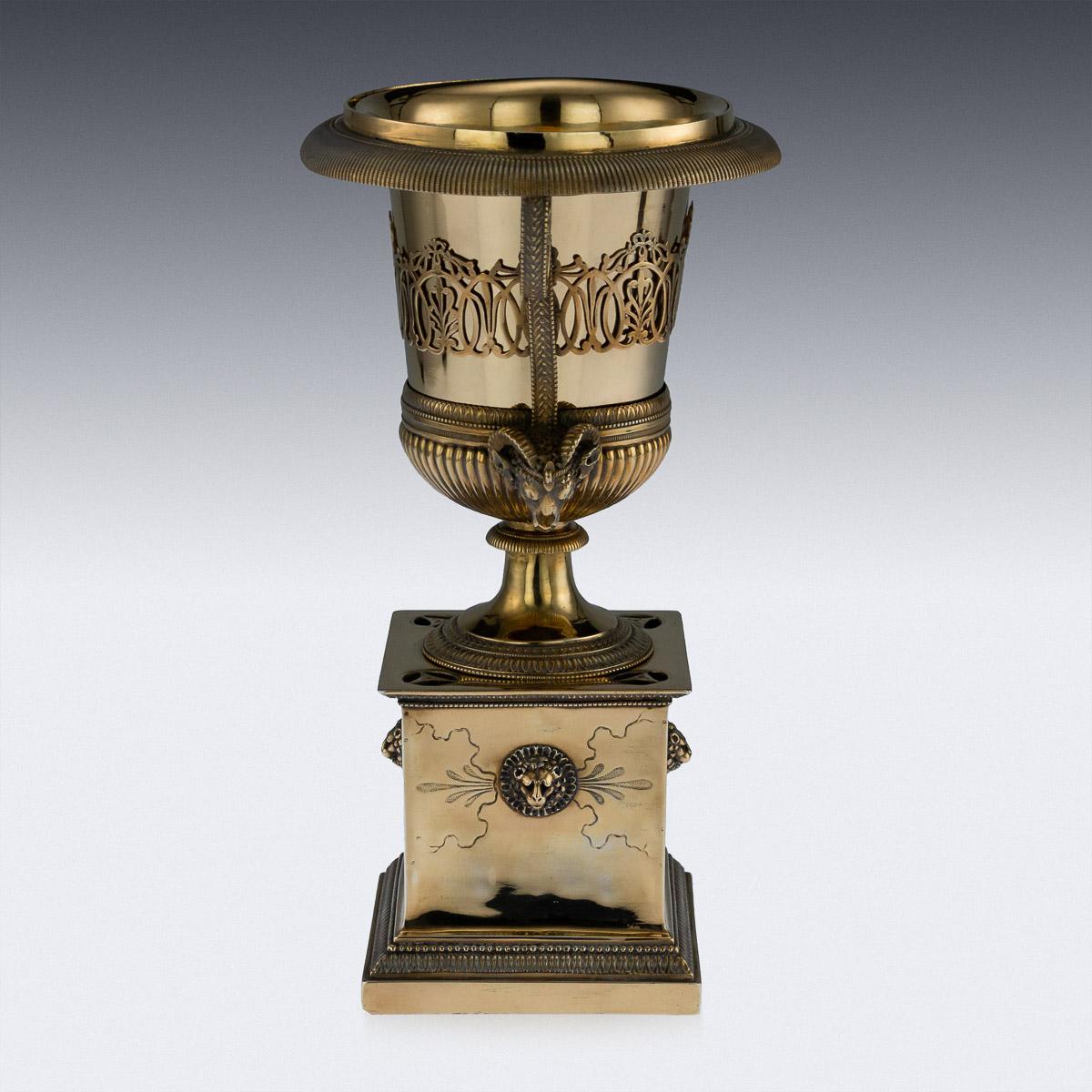 Antique early 19th century French Directoire style solid silver-gilt sugar urn, on a square podium base and fitted with a gilt-metal liner, urn applied with rams head handles and decorated with scrolling foliage, lacking a cover. All parts