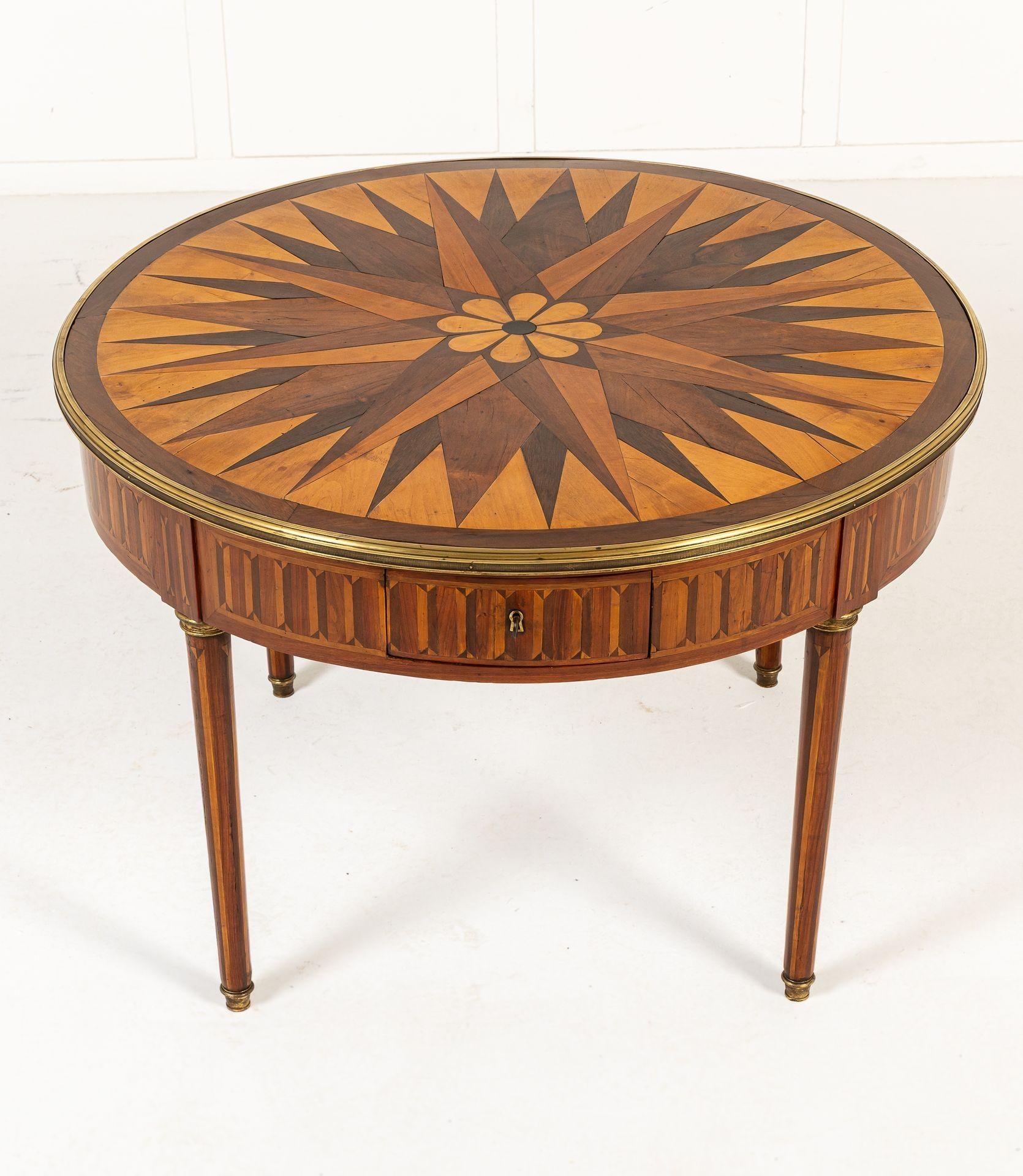Tavolo da centro in legno francese del XIX secolo. Di forma circolare, questo tavolo ha un bellissimo piano in parquet bordato da un bordo in ormolu. Il piano del tavolo è composto da vari esemplari di Wood incastonati in un motivo a stella con un