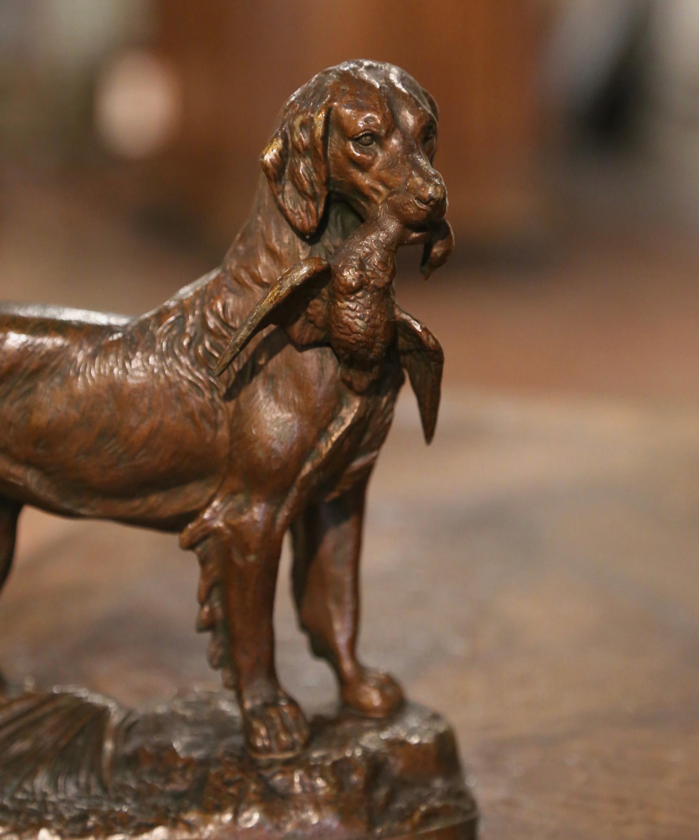 Decora la scrivania di un uomo o uno scaffale con questa antica scultura di cane e uccello. Creata in Francia intorno al 1870 e posta su una base ovale integrale, la composizione scultorea raffigura un setter che tiene in bocca un'anatra; la