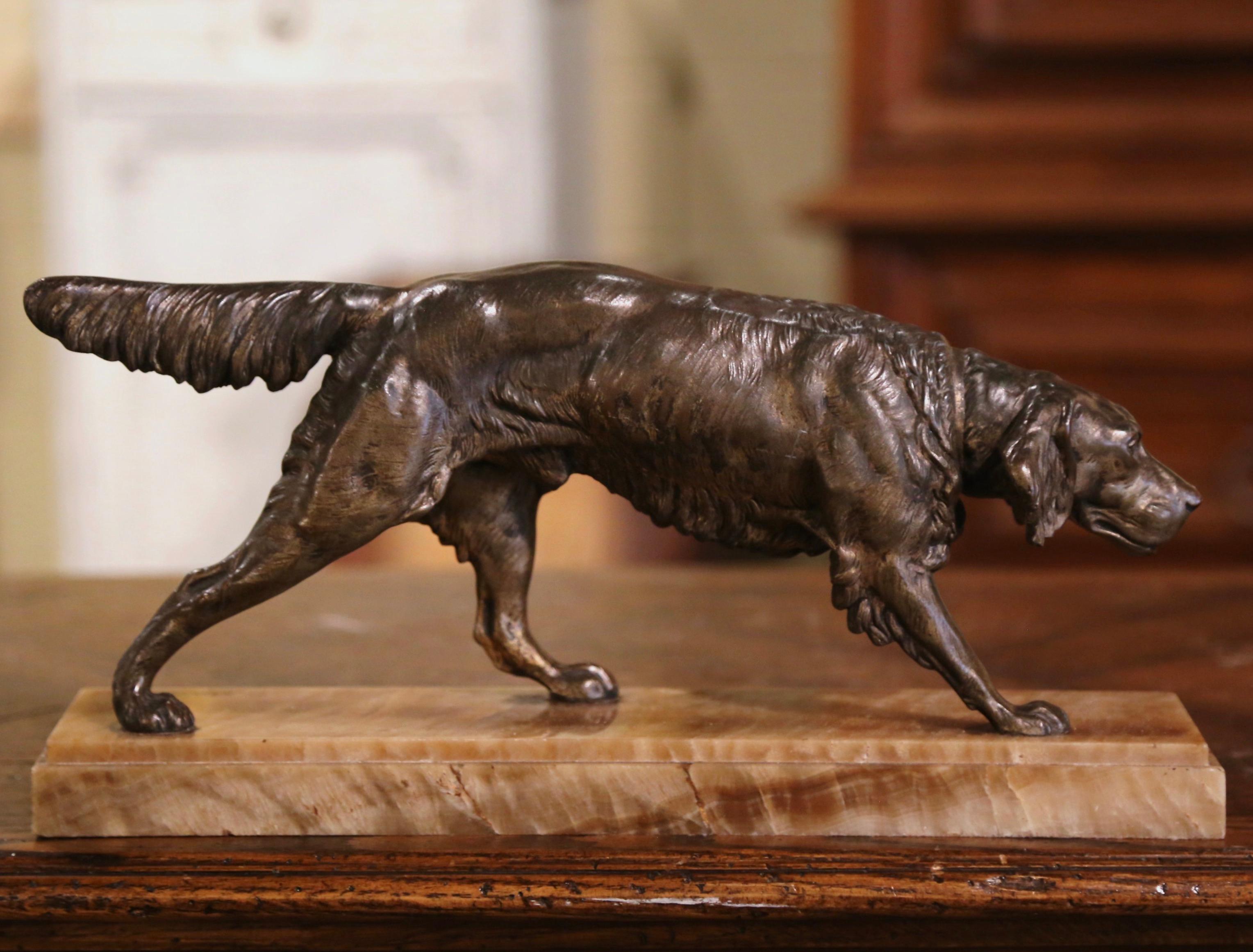 The antique spelter sculpture was created in France, circa 1870. Set on a rectangular variegated base, the work features an Irish setter pointing while lifting his front leg. The hunting dog figure is signed on the base, C. Masson. The piece is in