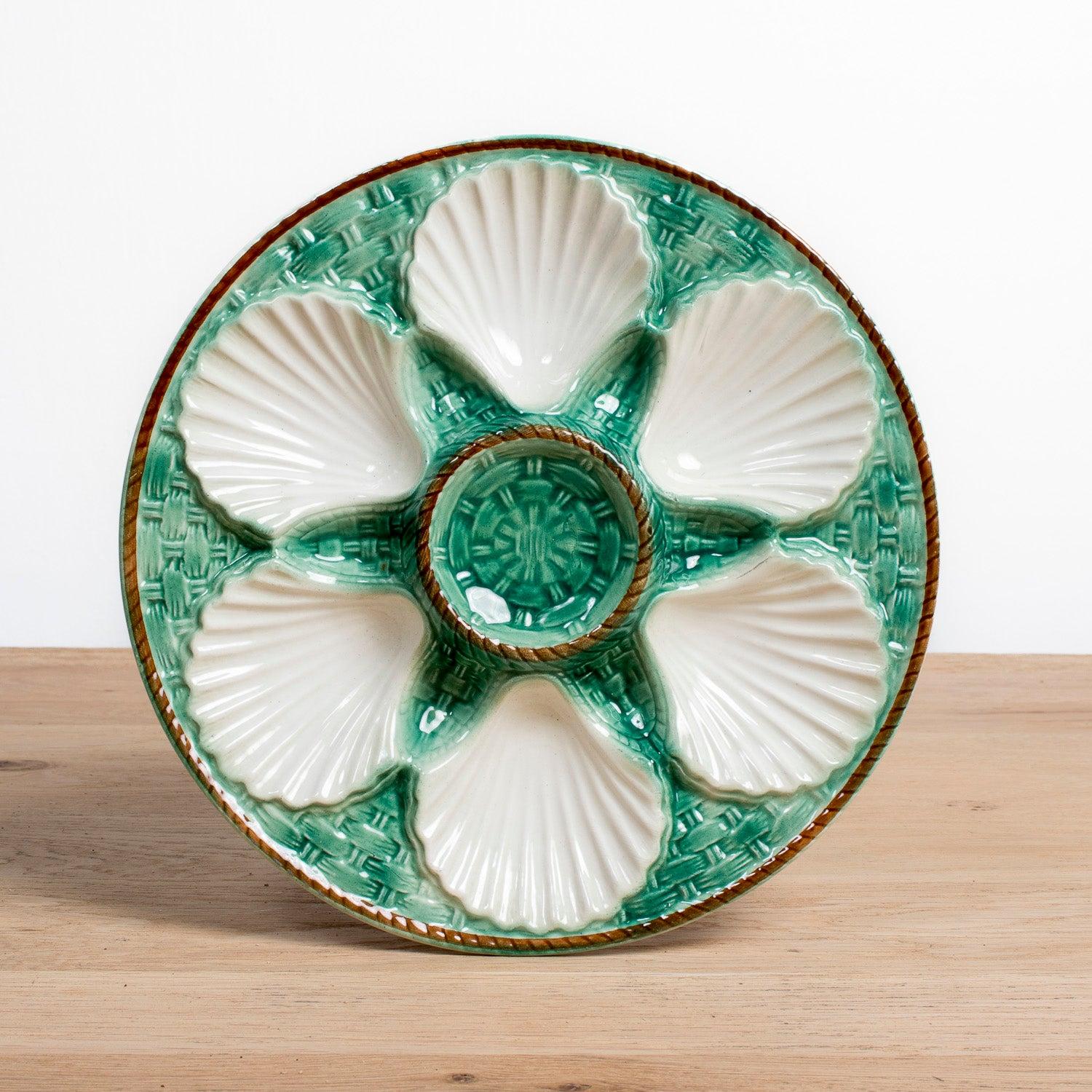 Beautiful French majolica oyster plates from the famed faïencerie of St. Clément, dating to the late 19th century, circa 1890s. Perfect for entertaining or display, each plate features six creamy white scallop shell-shaped wells surrounding a center