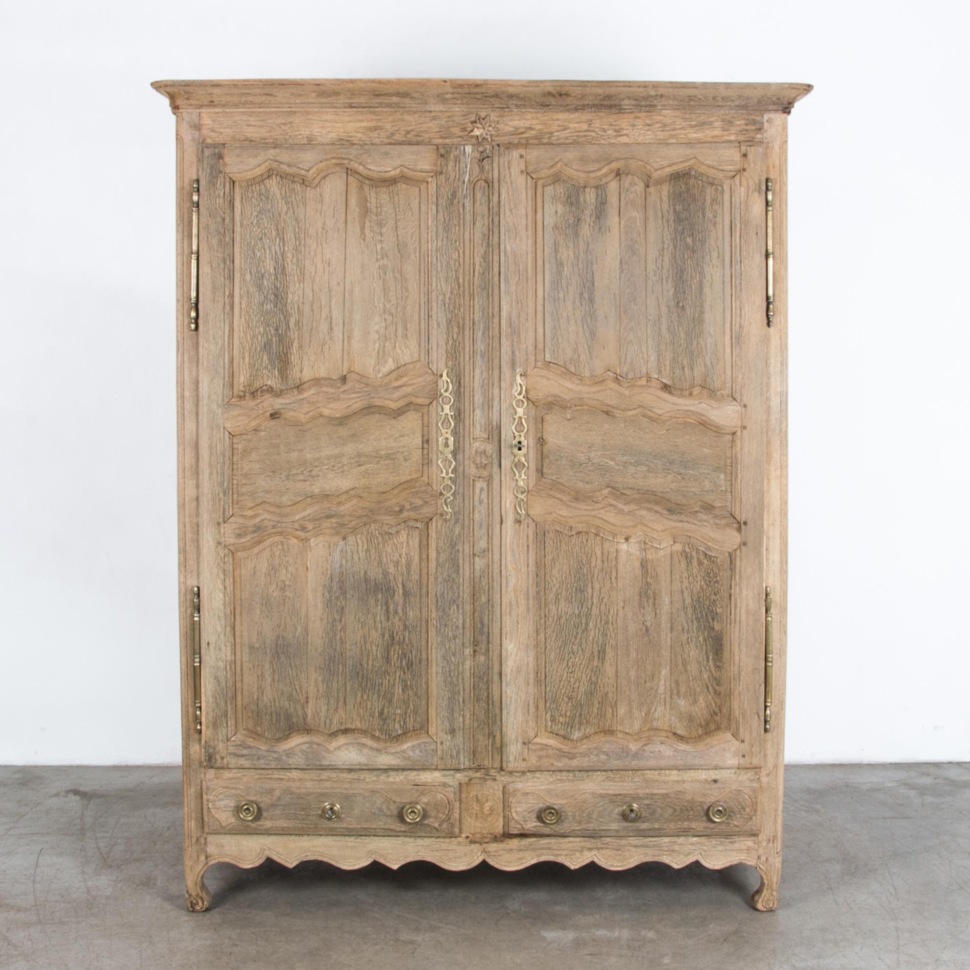 A French wardrobe from circa 1800 with distinctive cold growth oak in a rustic neutral finish. A spacious wide cabinet for wardrobe, pantry or other large storage with practical lower drawers. Time tested traditional craftsmanship, with original