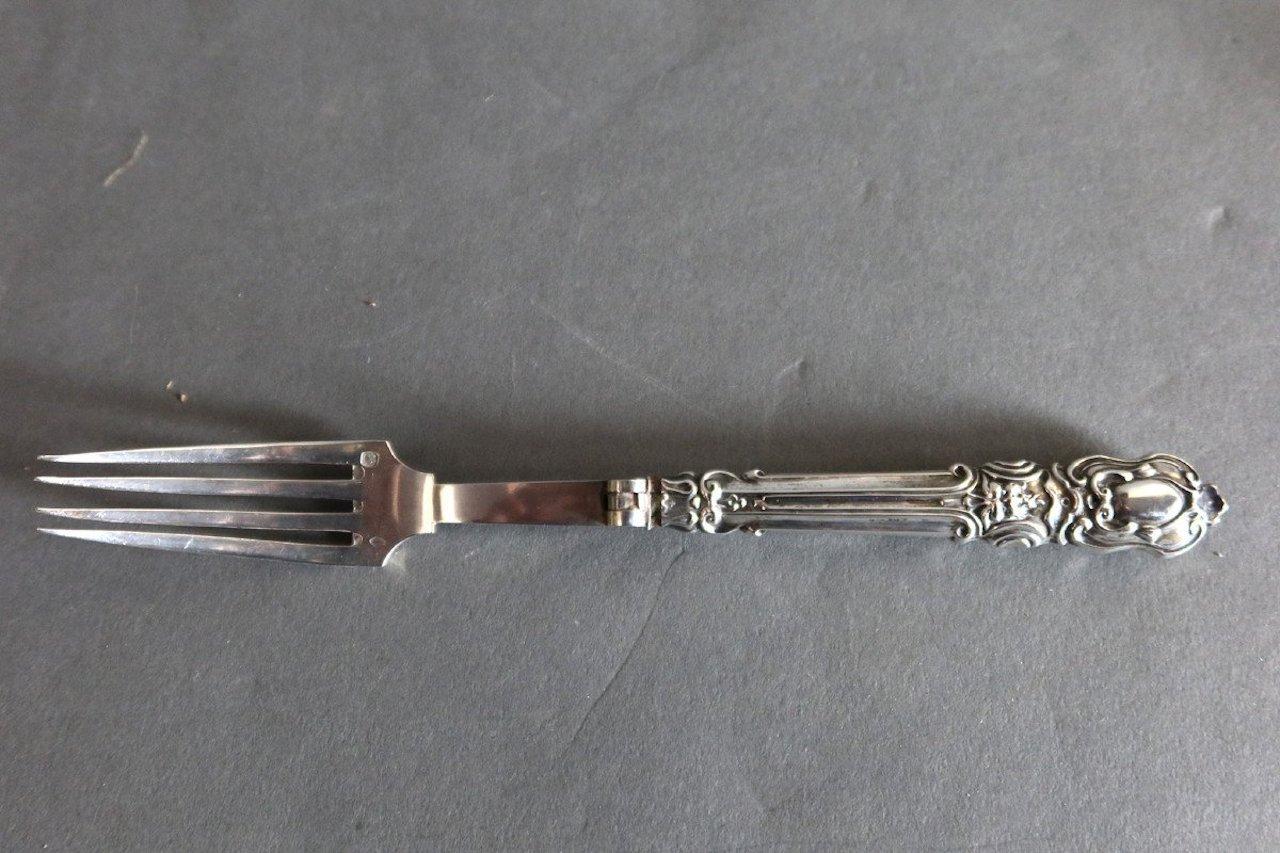 Folding travel case in sterling silver and silver filled with rococo style decoration which includes a spoon (18.5 cm) a fork (18.5 cm)
and a knife (17.5 cm) with metal blade. 
Punch Minerve. Gross weight: 122g.