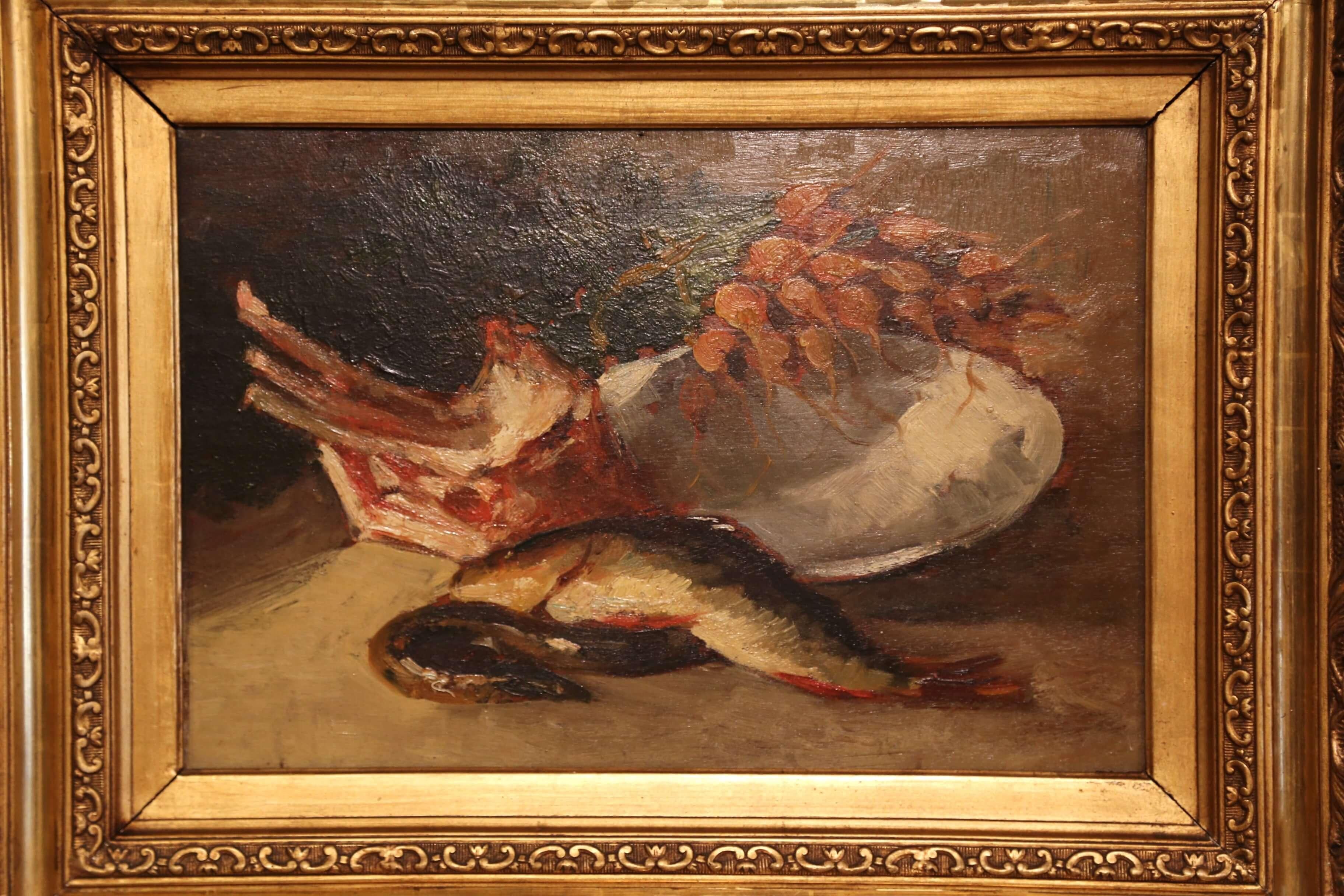 This still-life painting was created in France, circa 1870. Set in an ornate carved giltwood frame, the art work features a typical still life food display on table cloth including a fish and heel, a bunch of radishes and some ribs on a white plate.