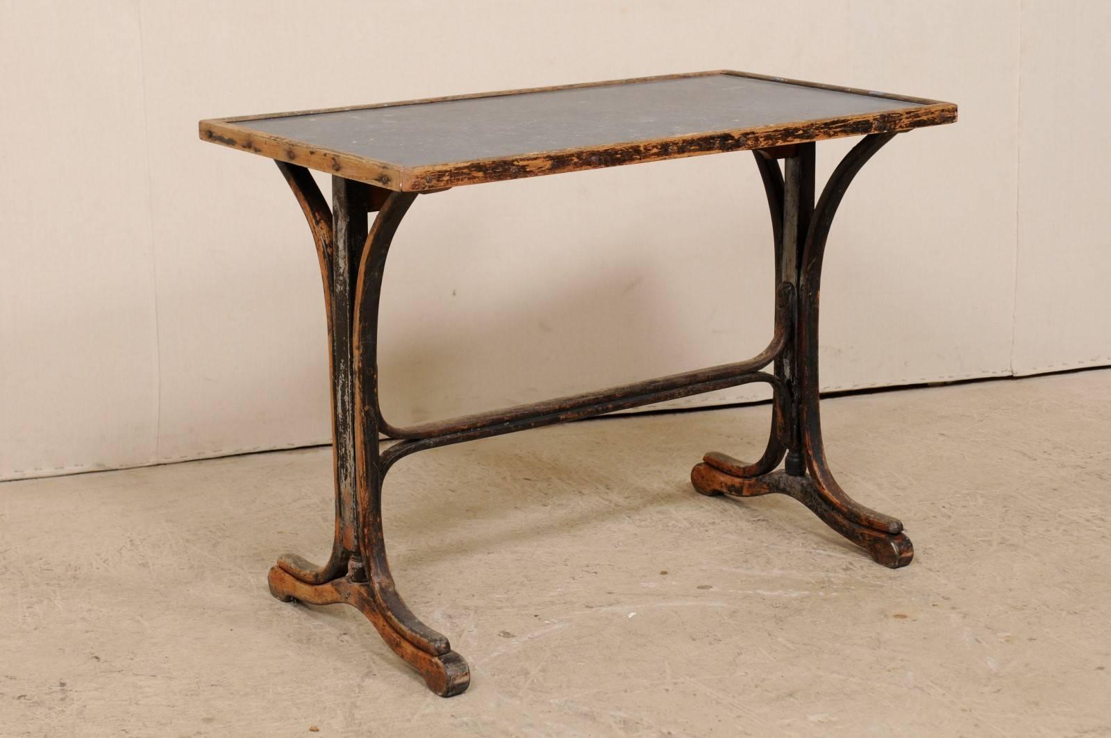 A 19th century French table with stone top. This antique French table features a honed stone top set within a wood-edged frame, over a trestle style wooden base. The wooden base of this table has a fantastic old patina with grey paint and lovely